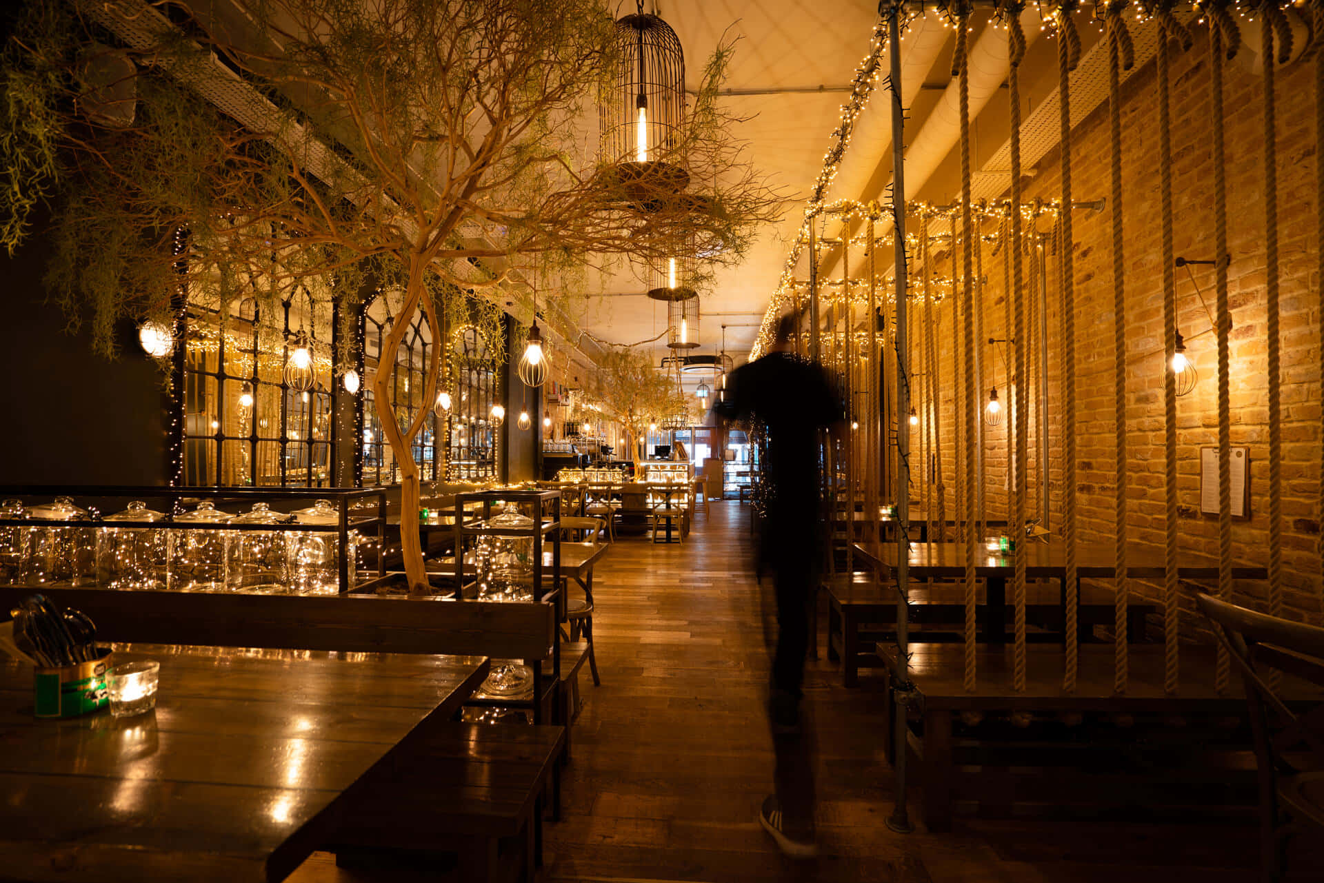 Dimly Lit Restaurant Interiorwith Person Walking Wallpaper