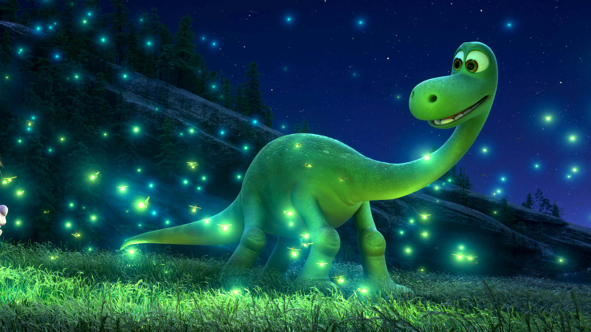 En grøn tegnefilm dinosaur stående på toppen af en bakke, som tager det smukke landskab i sig.