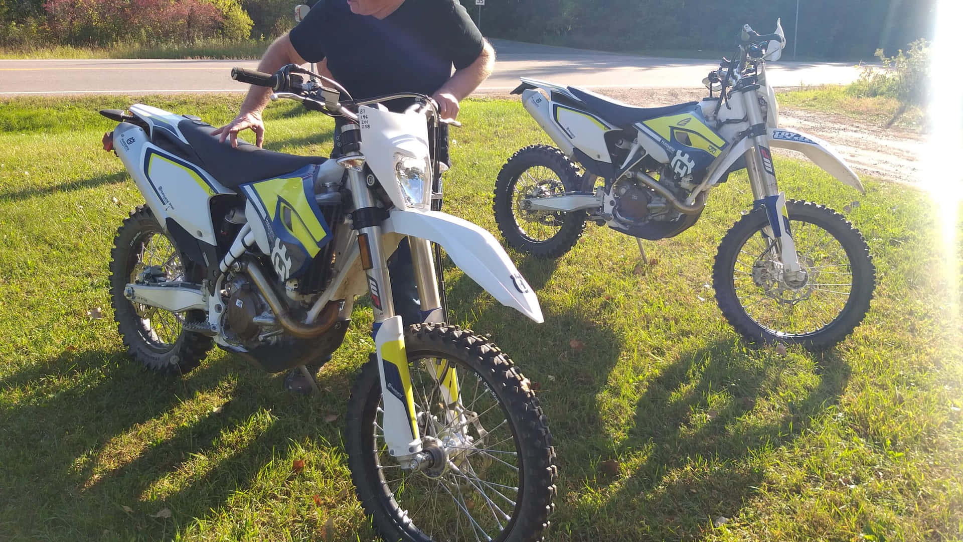 Two Dirt Bikes Parked On The Grass