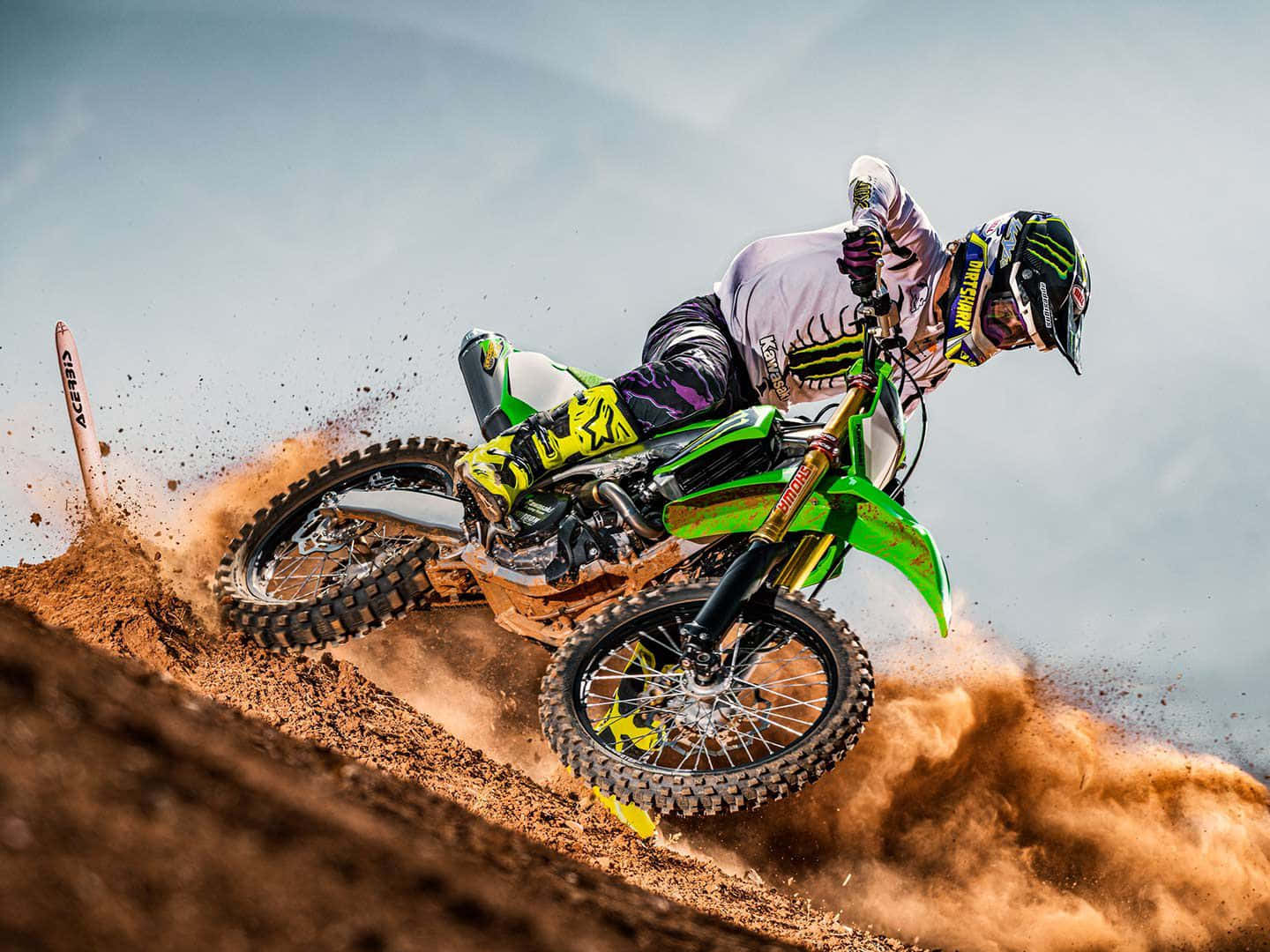 A Person Riding A Green Dirt Bike On A Dirt Track
