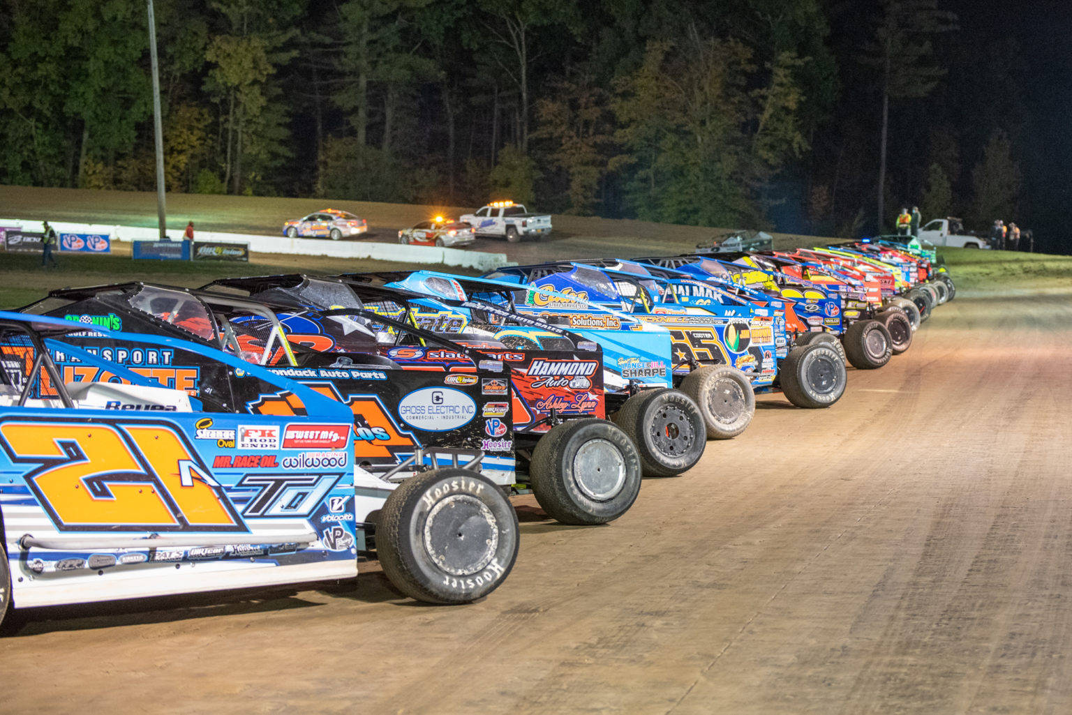 A Line Of Dirt Track Racing Cars At Night Wallpaper