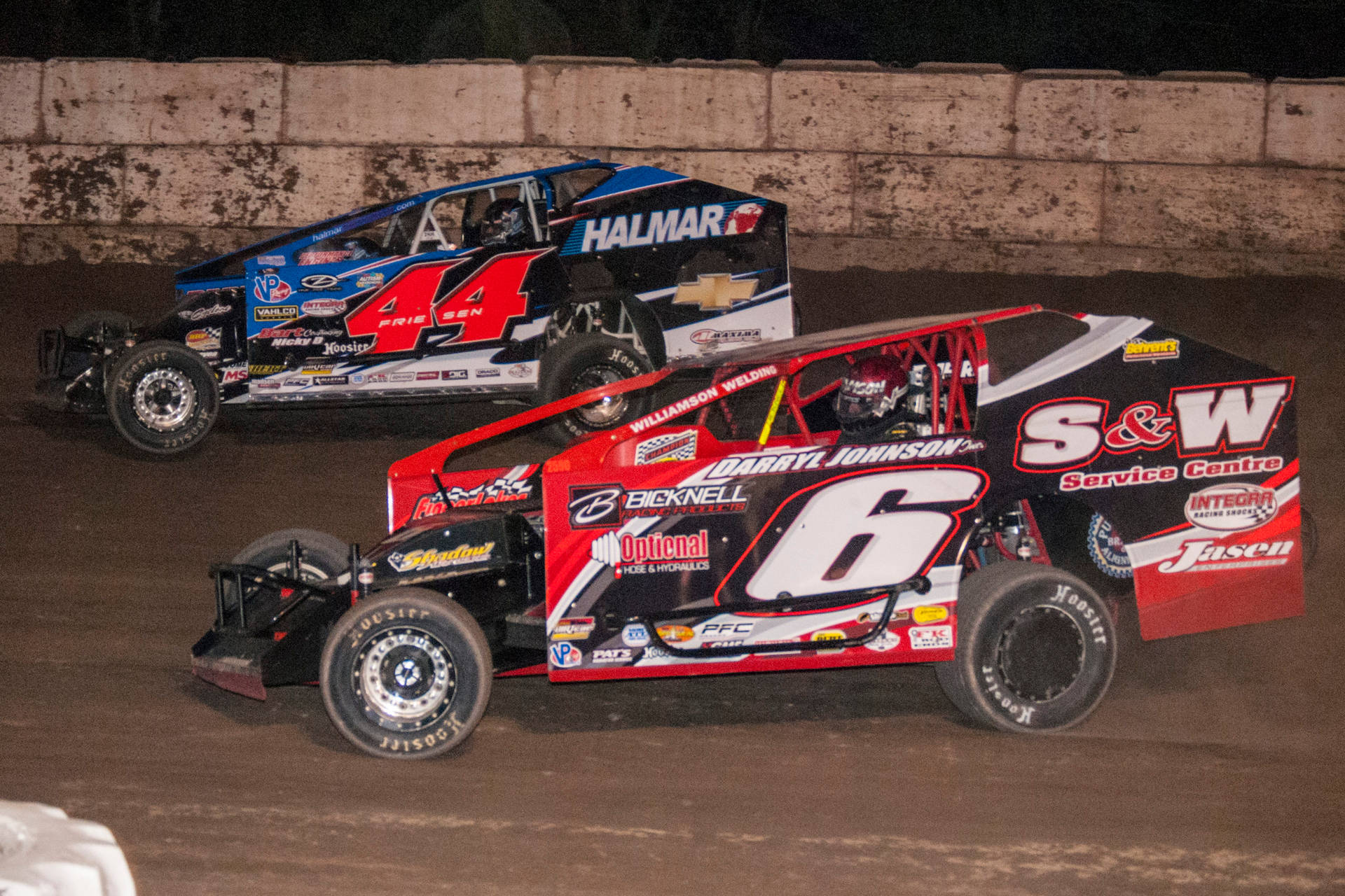 Two Dirt Race Cars Racing On A Dirt Track Wallpaper