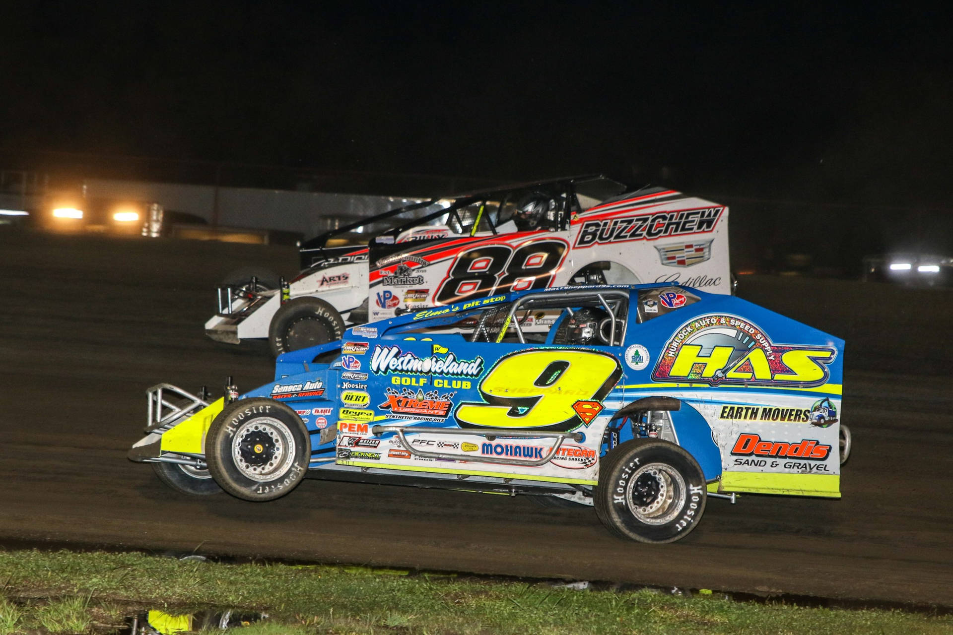 Two Dirt Race Cars Racing On A Dirt Track At Night Wallpaper