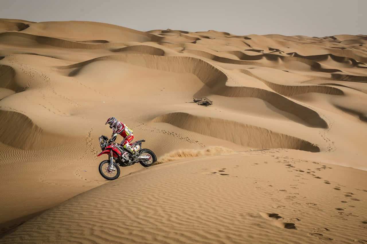 A Person Riding A Red Dirt Bike On A Desert