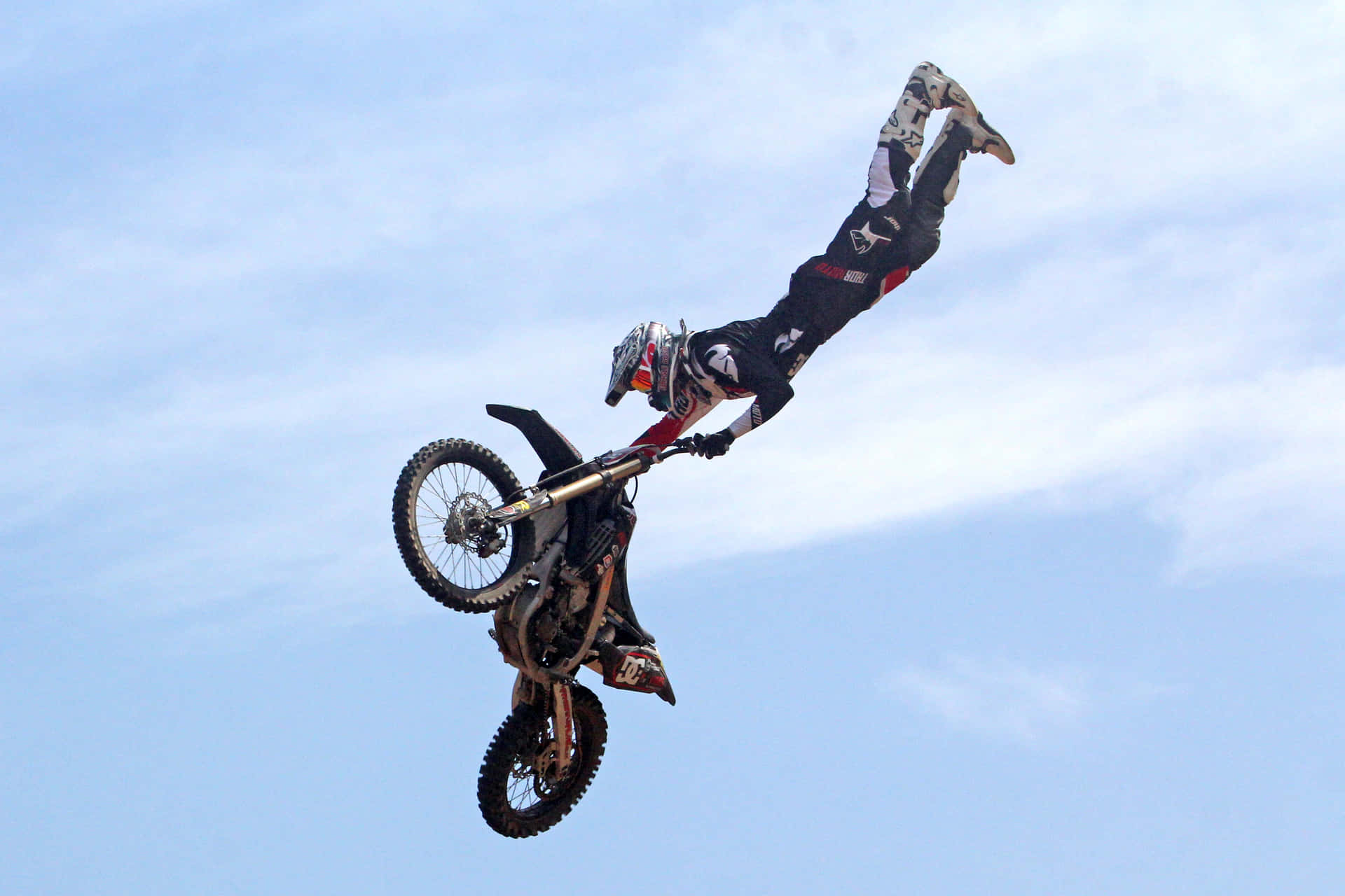 A motocross rider soaring through the air on his dirt bike