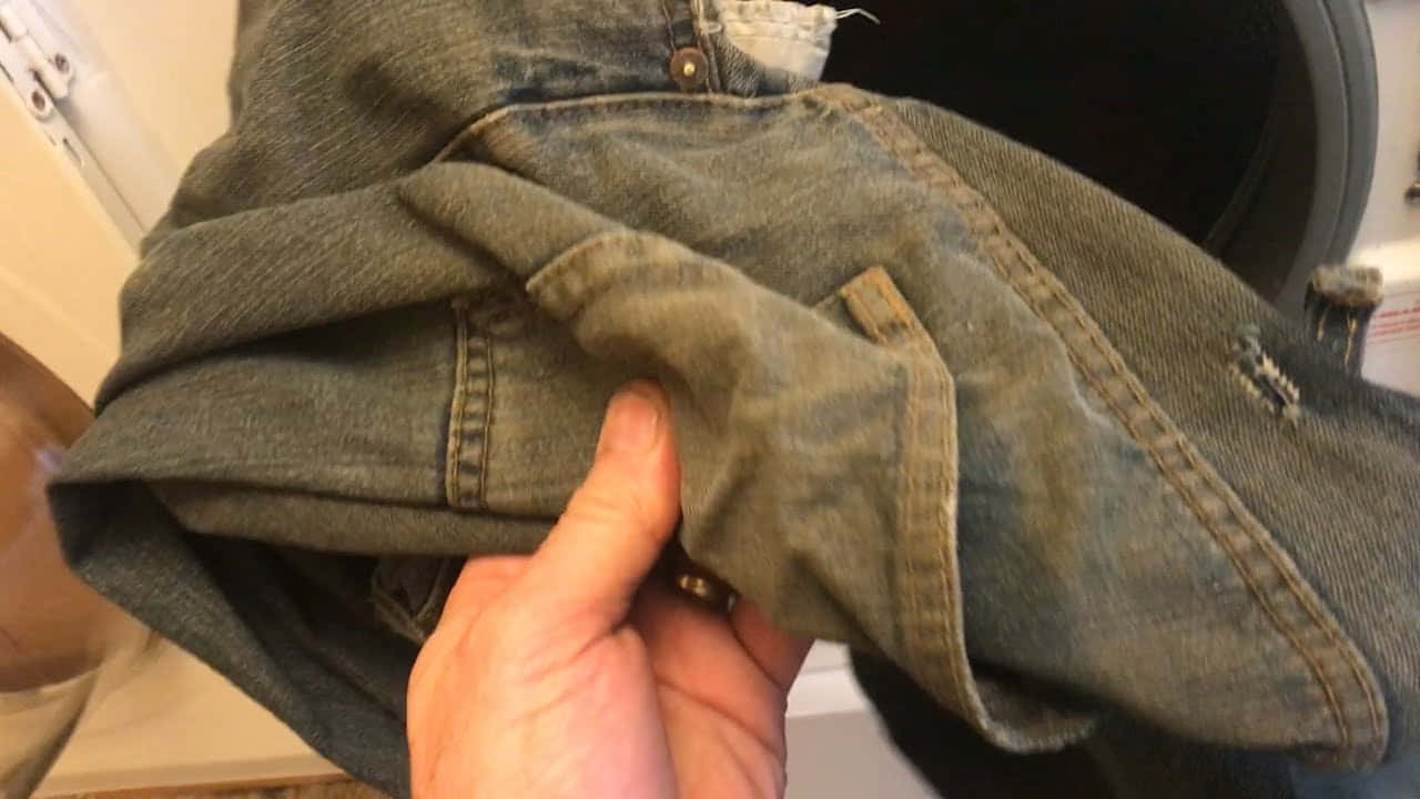 a person holding a pair of jeans in a laundry room