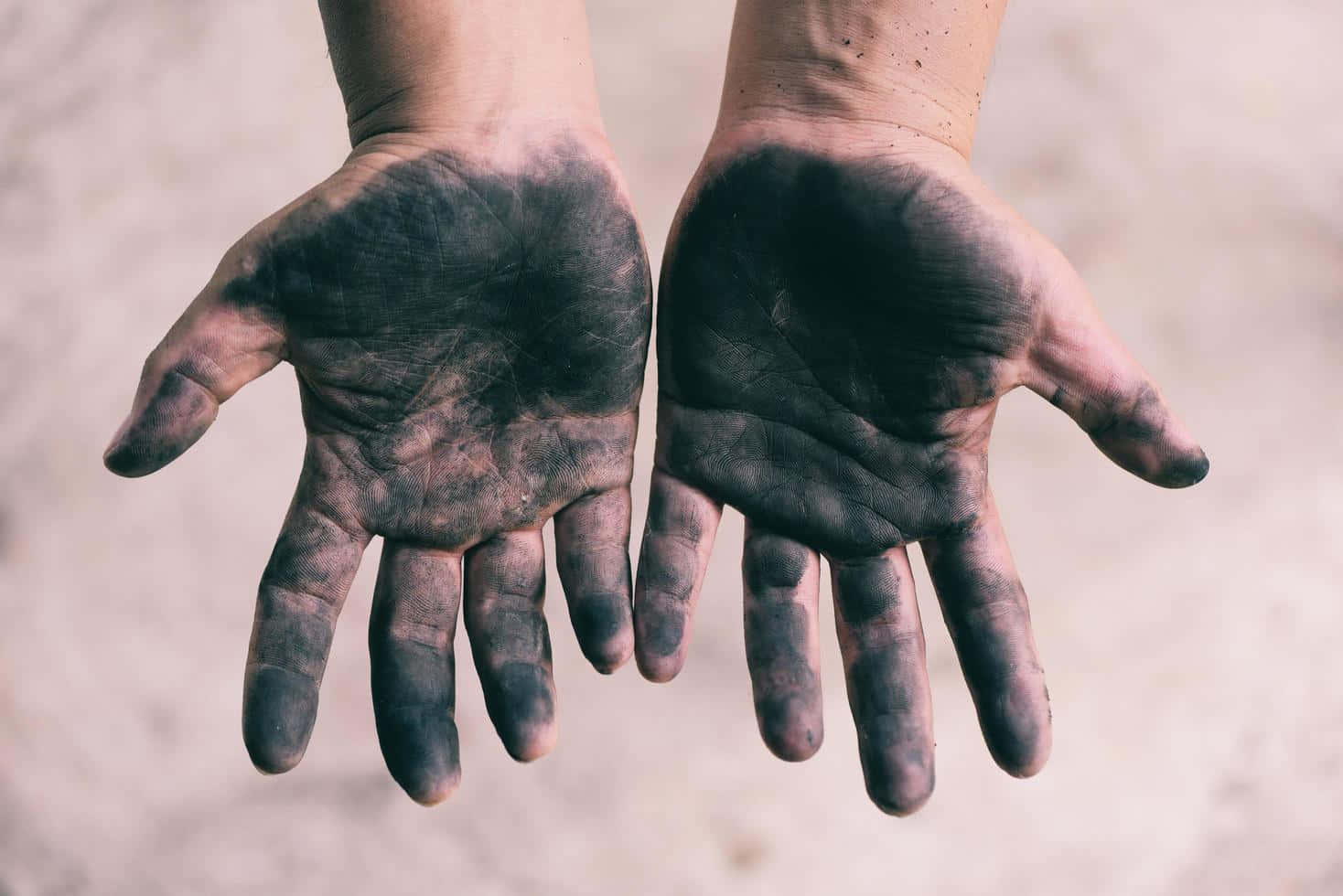 two hands with black dirt on them