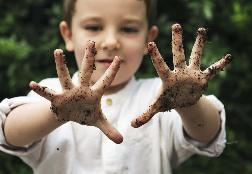 a young boy with his hands covered in dirt