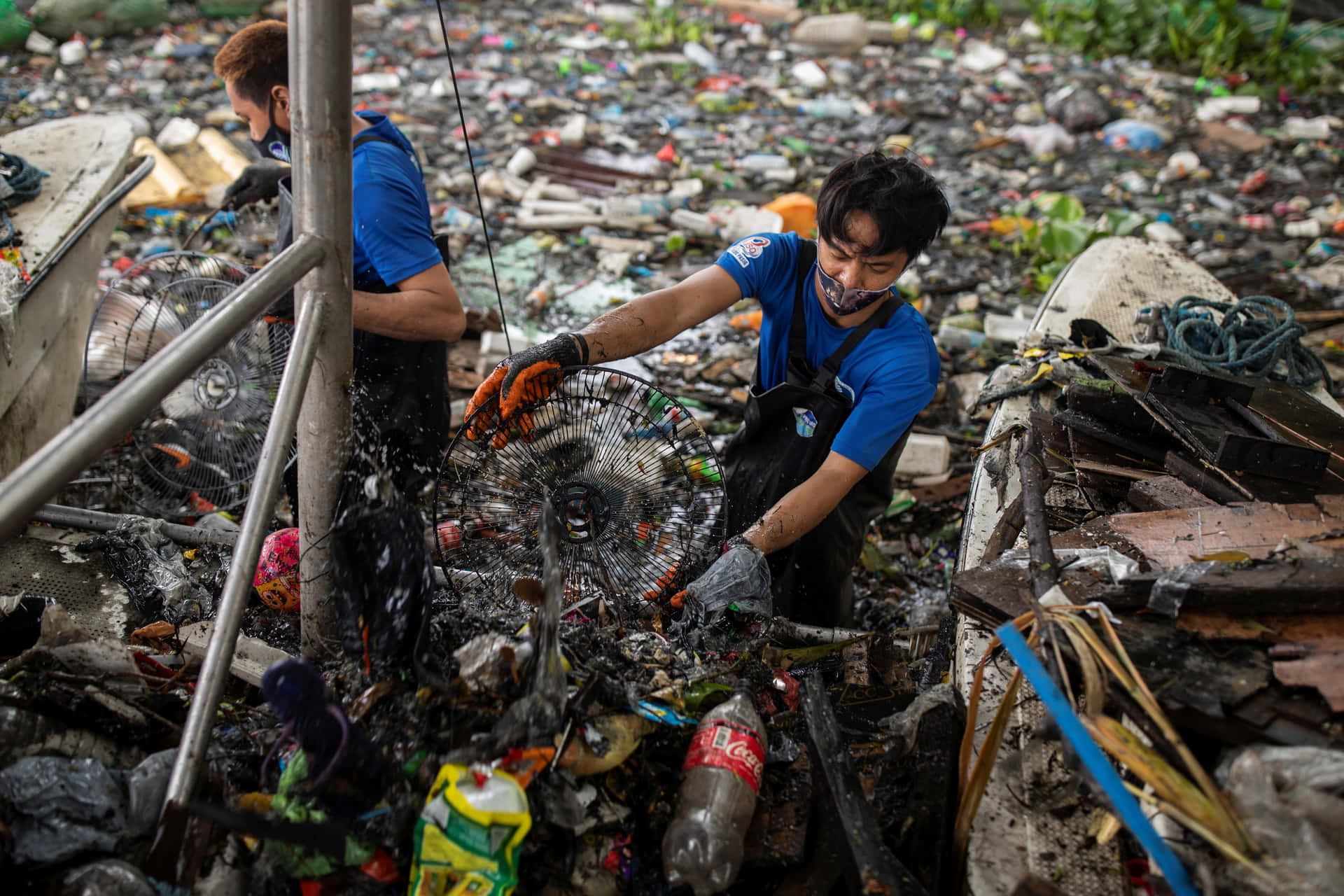two men are cleaning up garbage in a trash pile