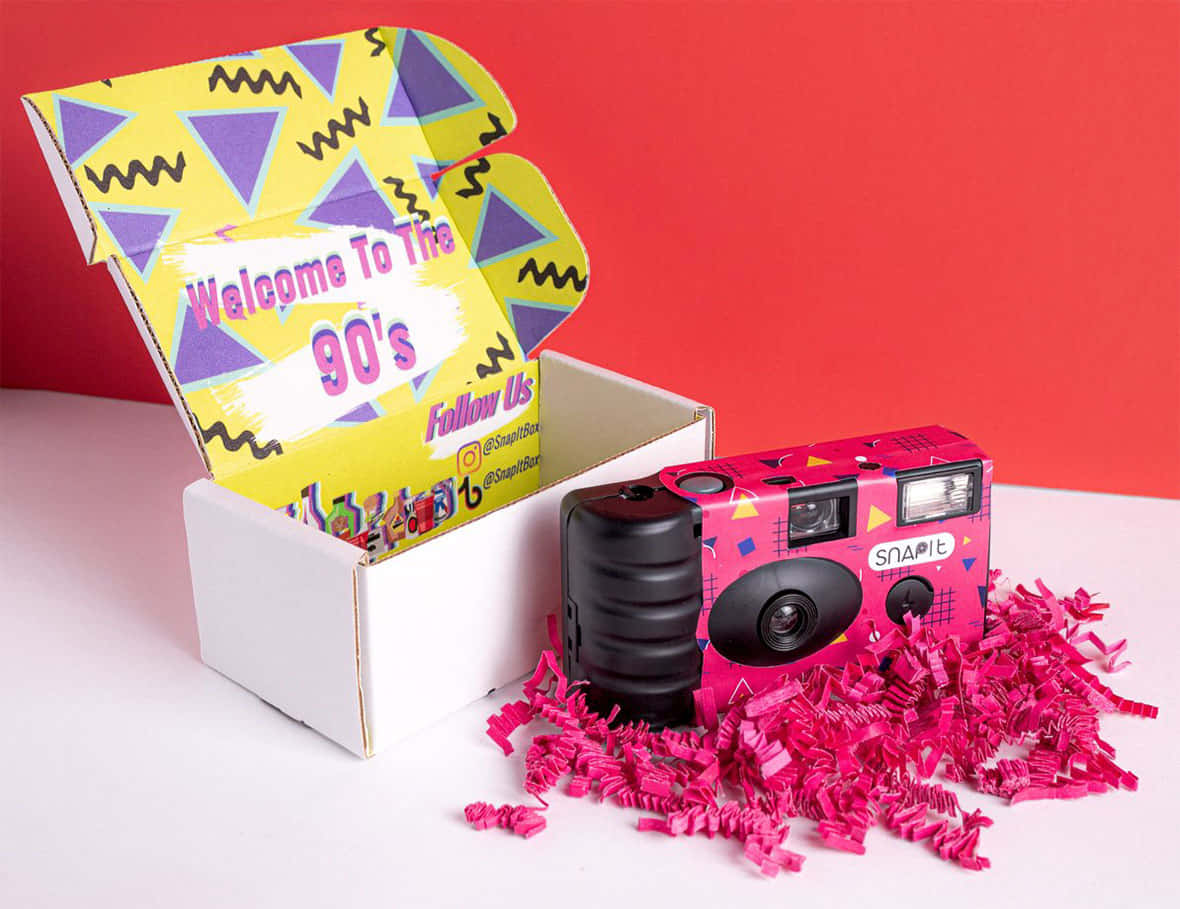 En pink kamera sidder ved siden af ​​et boks pink tisspapir