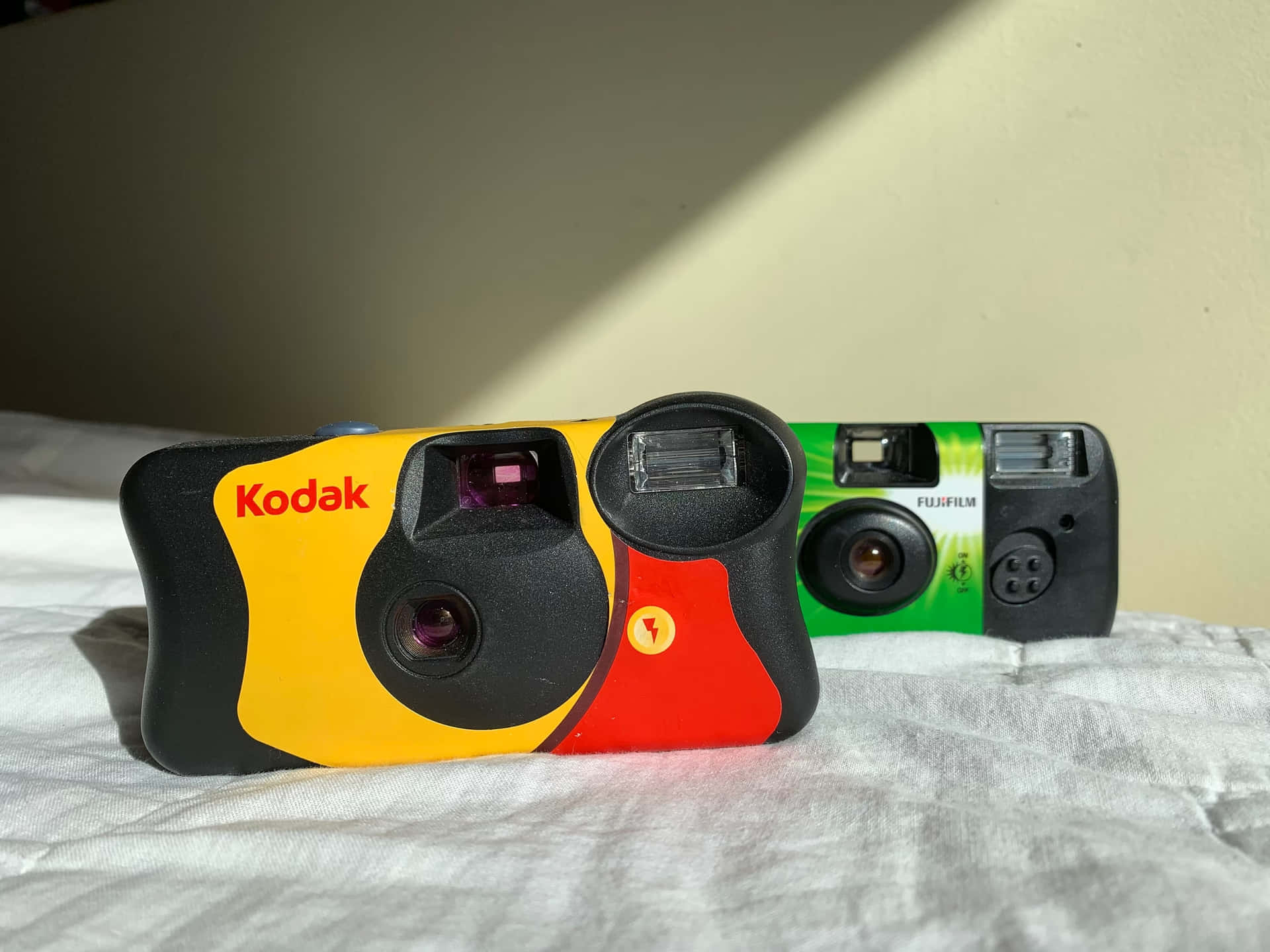 Two Kodak Cameras On A Bed