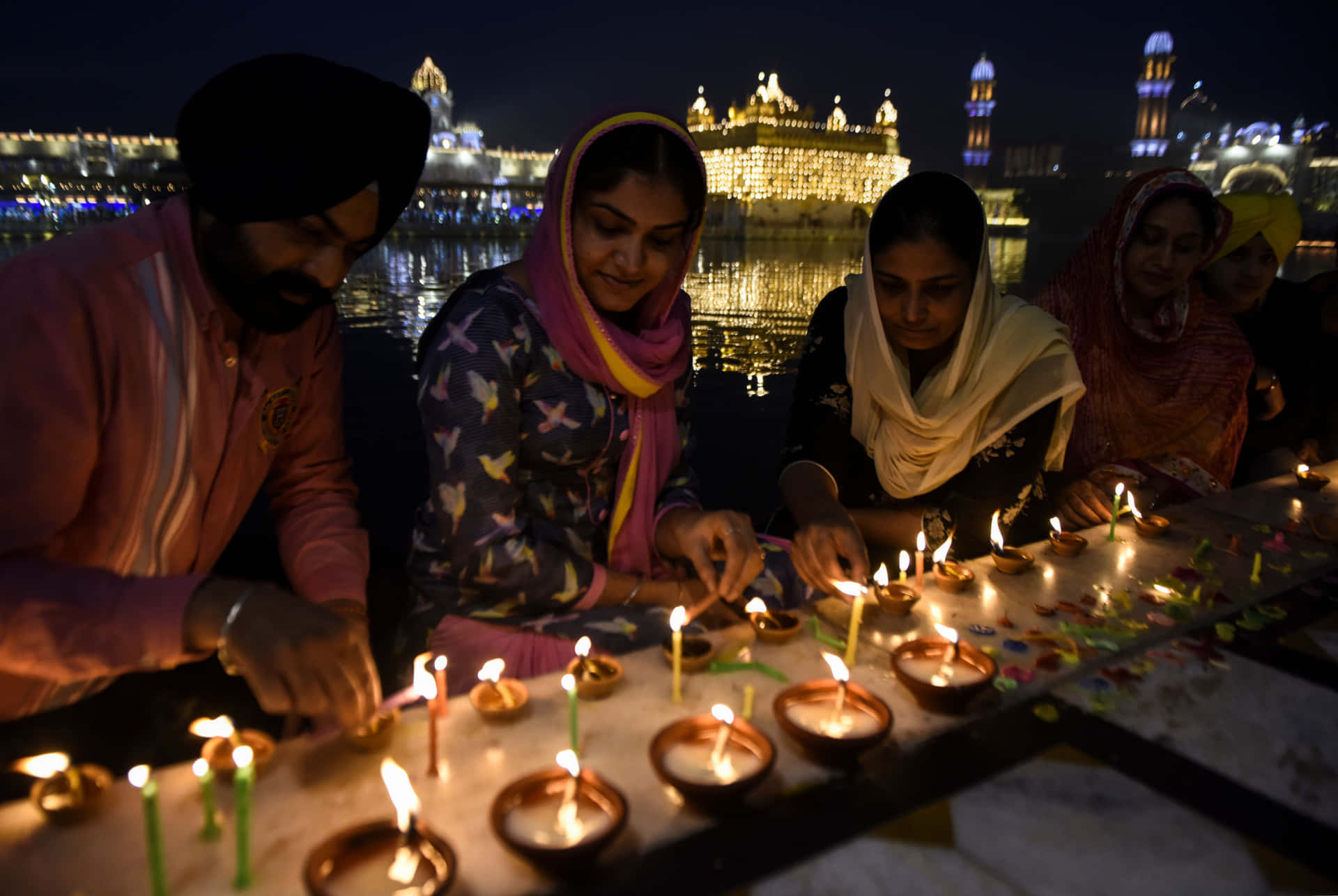 People Lighting Candles In Front Of The Golden Temple