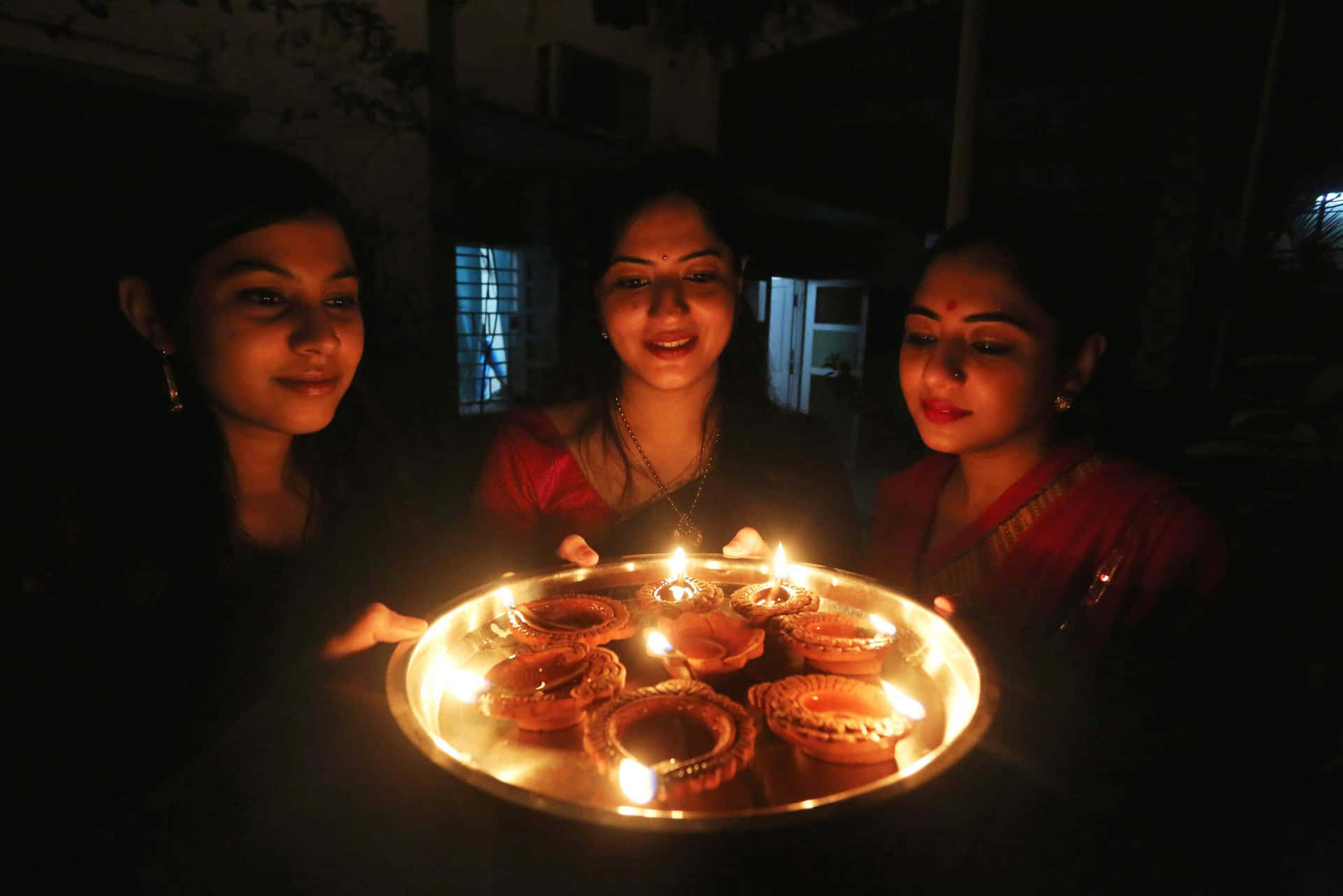 Dreifrauen Halten Kerzen Vor Einem Teller.