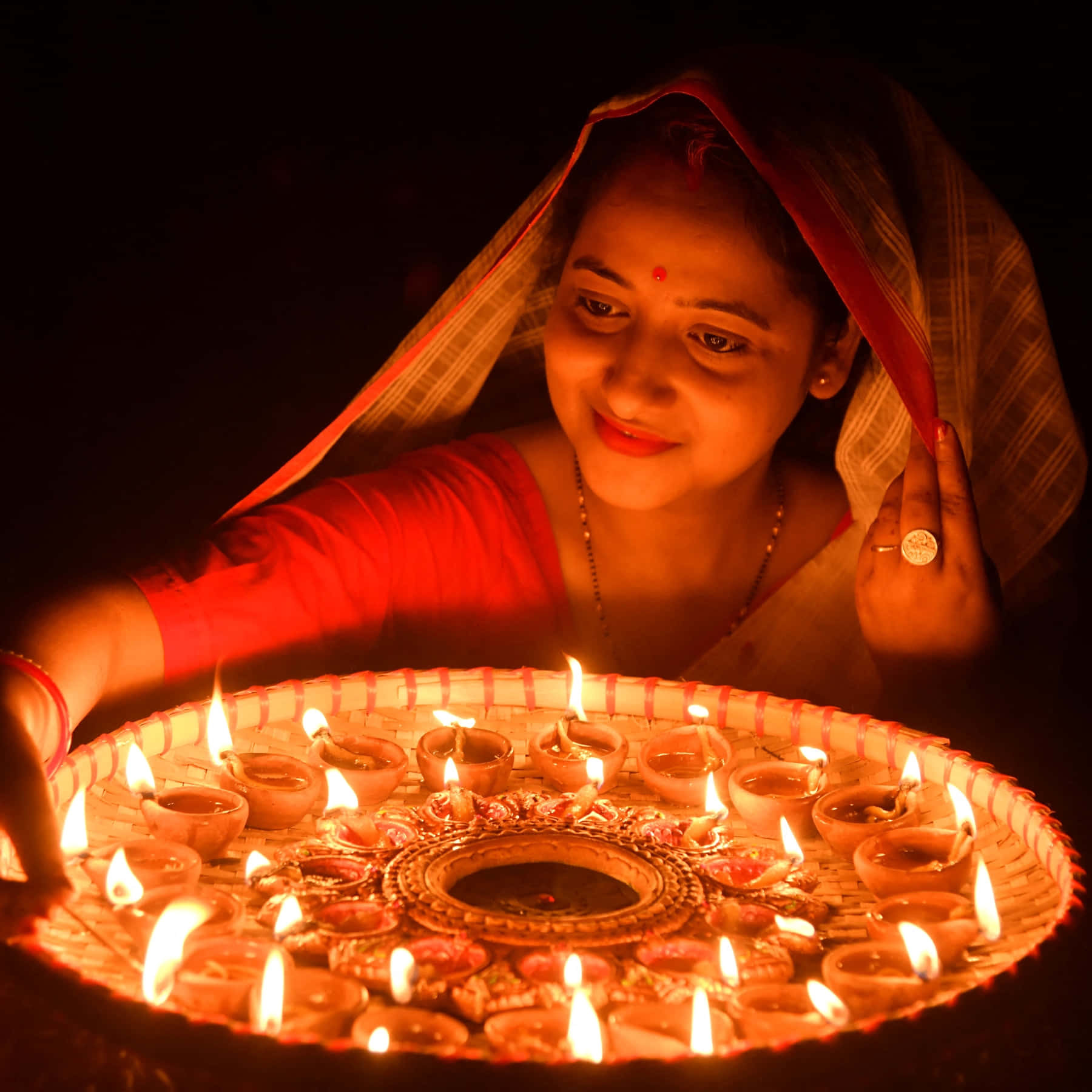 A Woman Lighting A Candle In Front Of A Large Platter