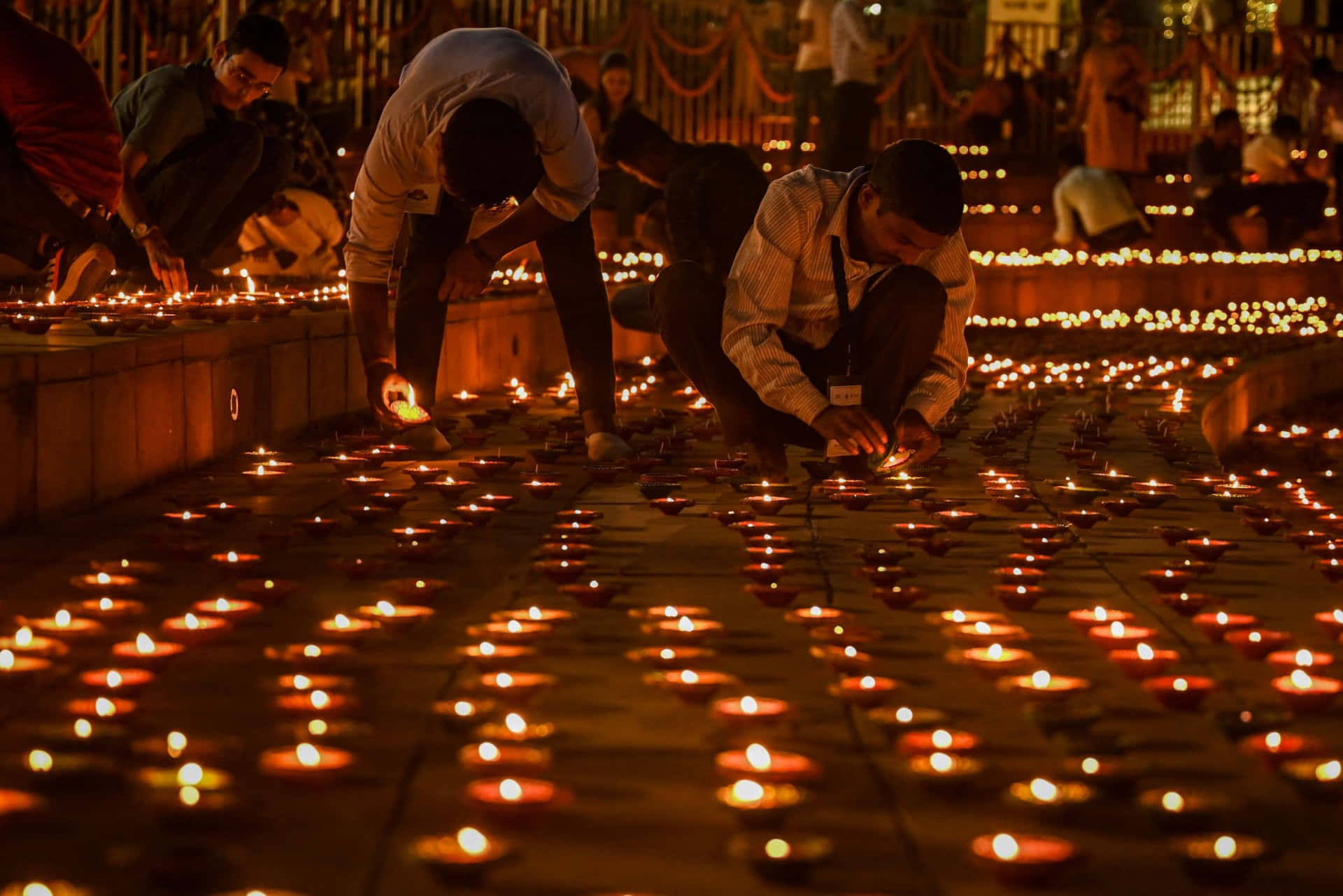 People Lighting Candles On The Ground In Front Of A Building