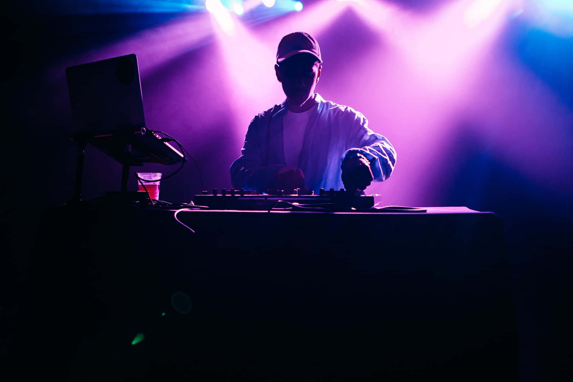 A captivating DJ spinning beats under the spell of vibrant neon lights