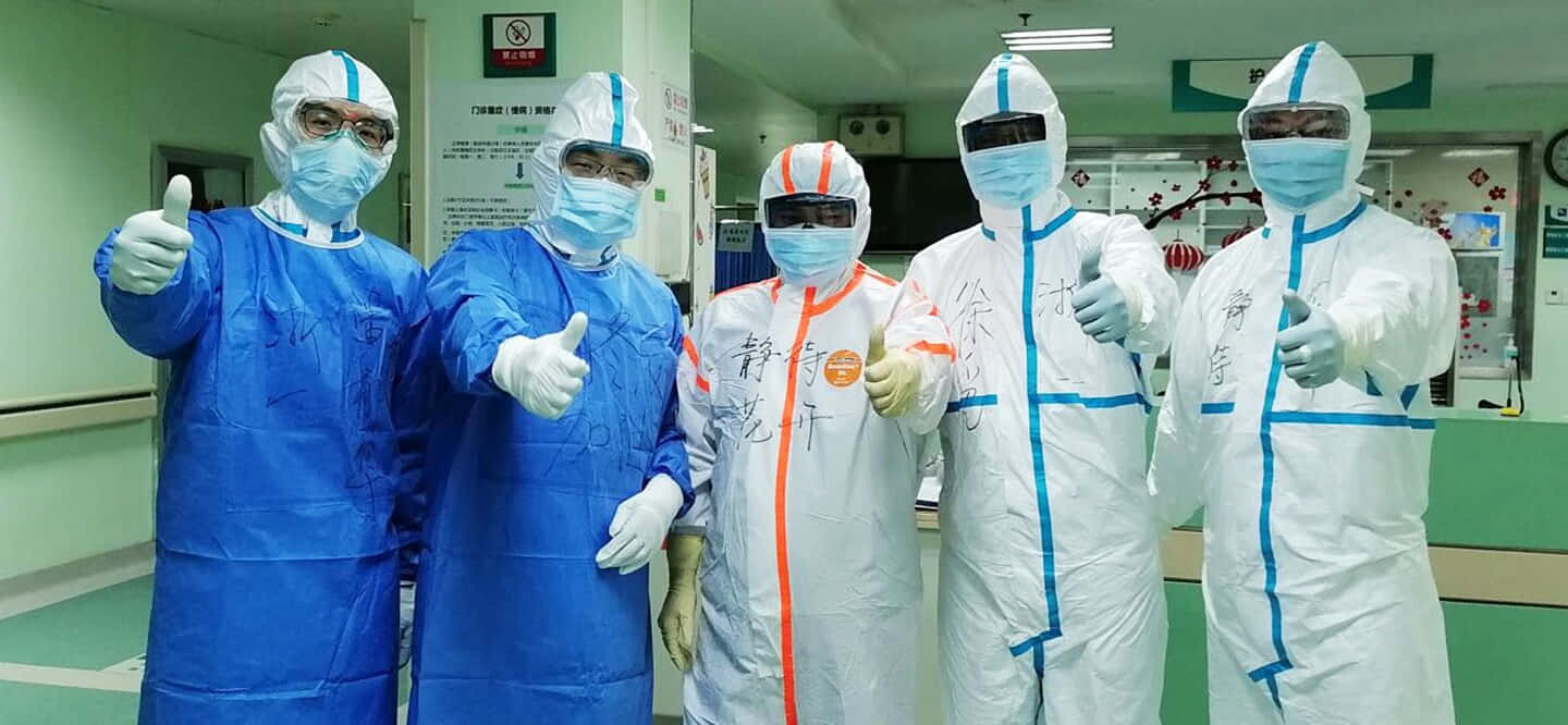 Four People In Protective Suits Standing In A Hospital