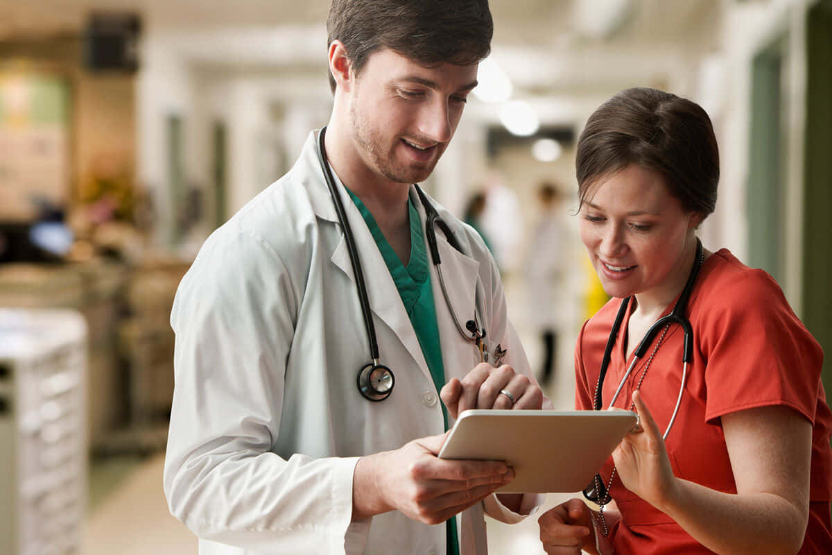Duemedici Che Guardano Un Tablet In Un Corridoio Dell'ospedale