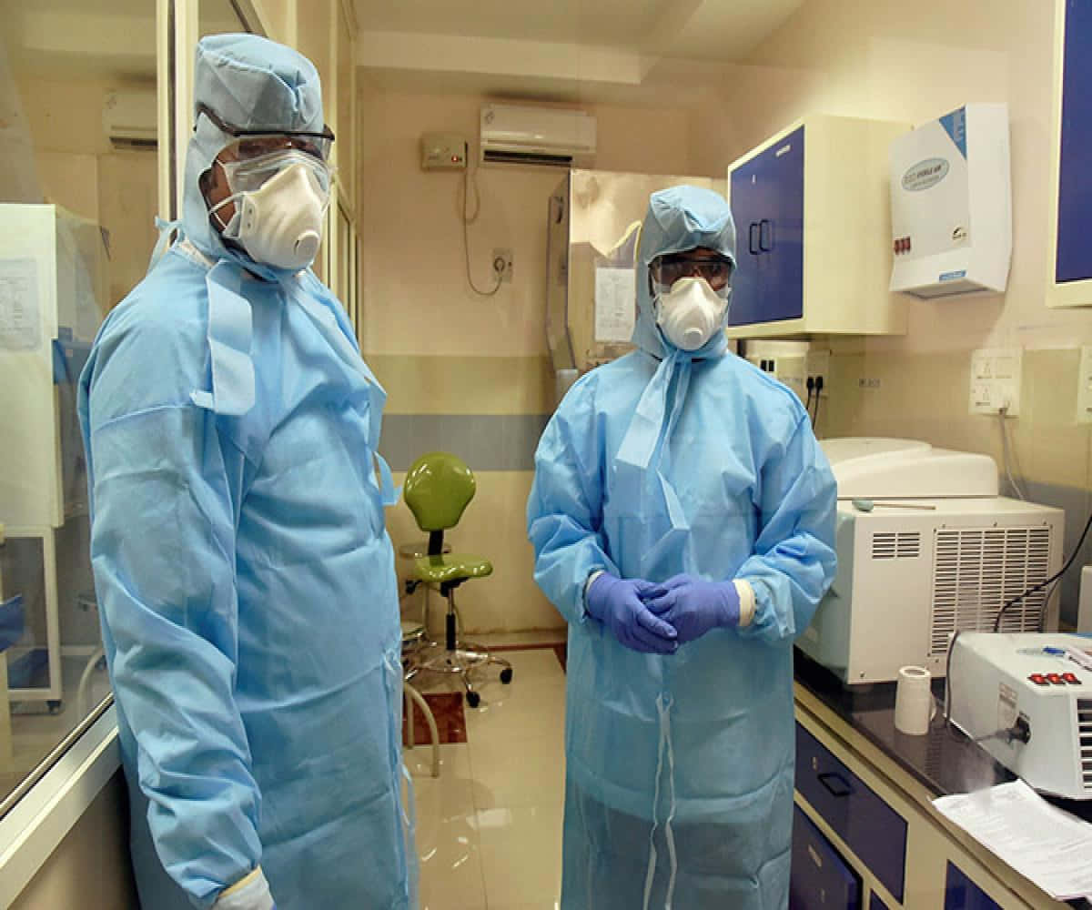 Tvåpersoner I Skyddsdräkter Står I Ett Laboratorium