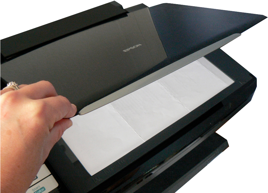 Document Scanningin Progress PNG — A hand with a ring lifts the lid of a black Epson scanner revealing a blank sheet of paper inside.