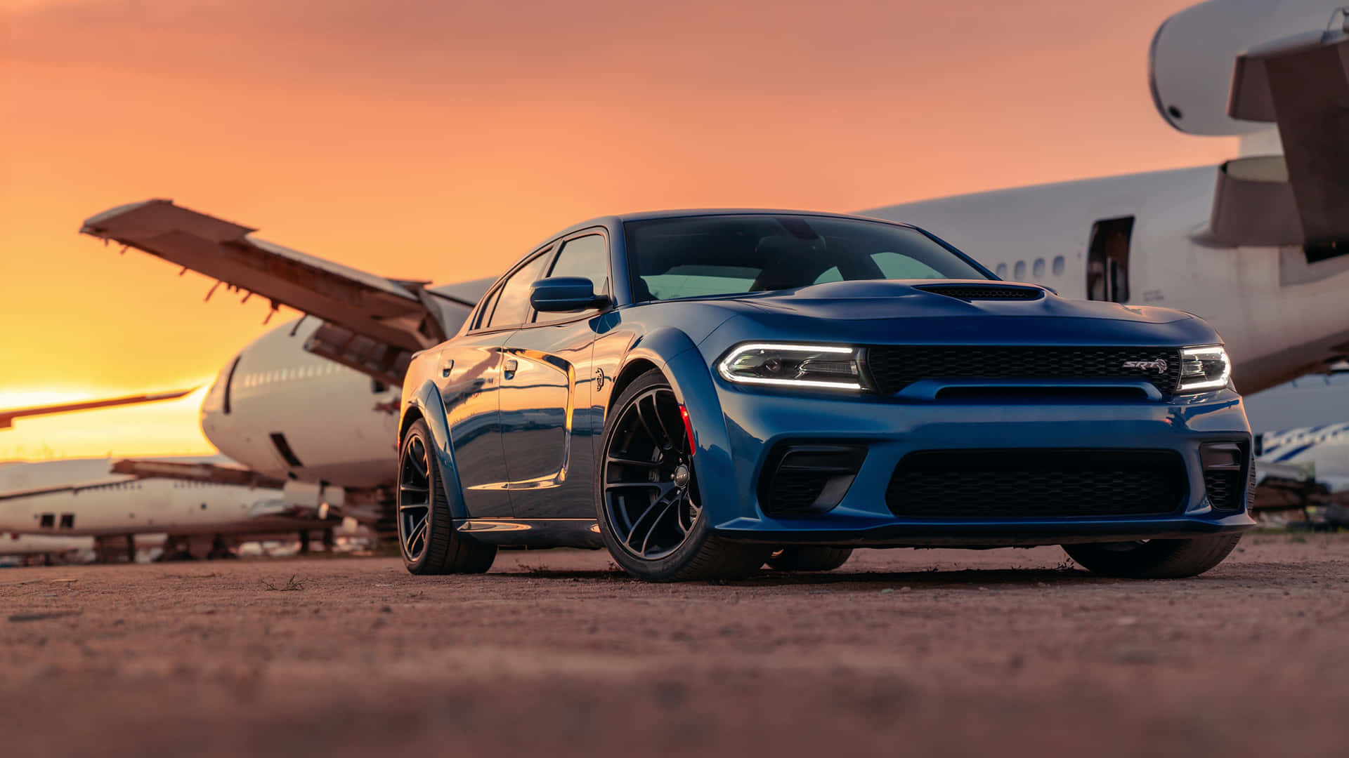 The Blue Dodge Charger Parked In Front Of An Airplane Wallpaper