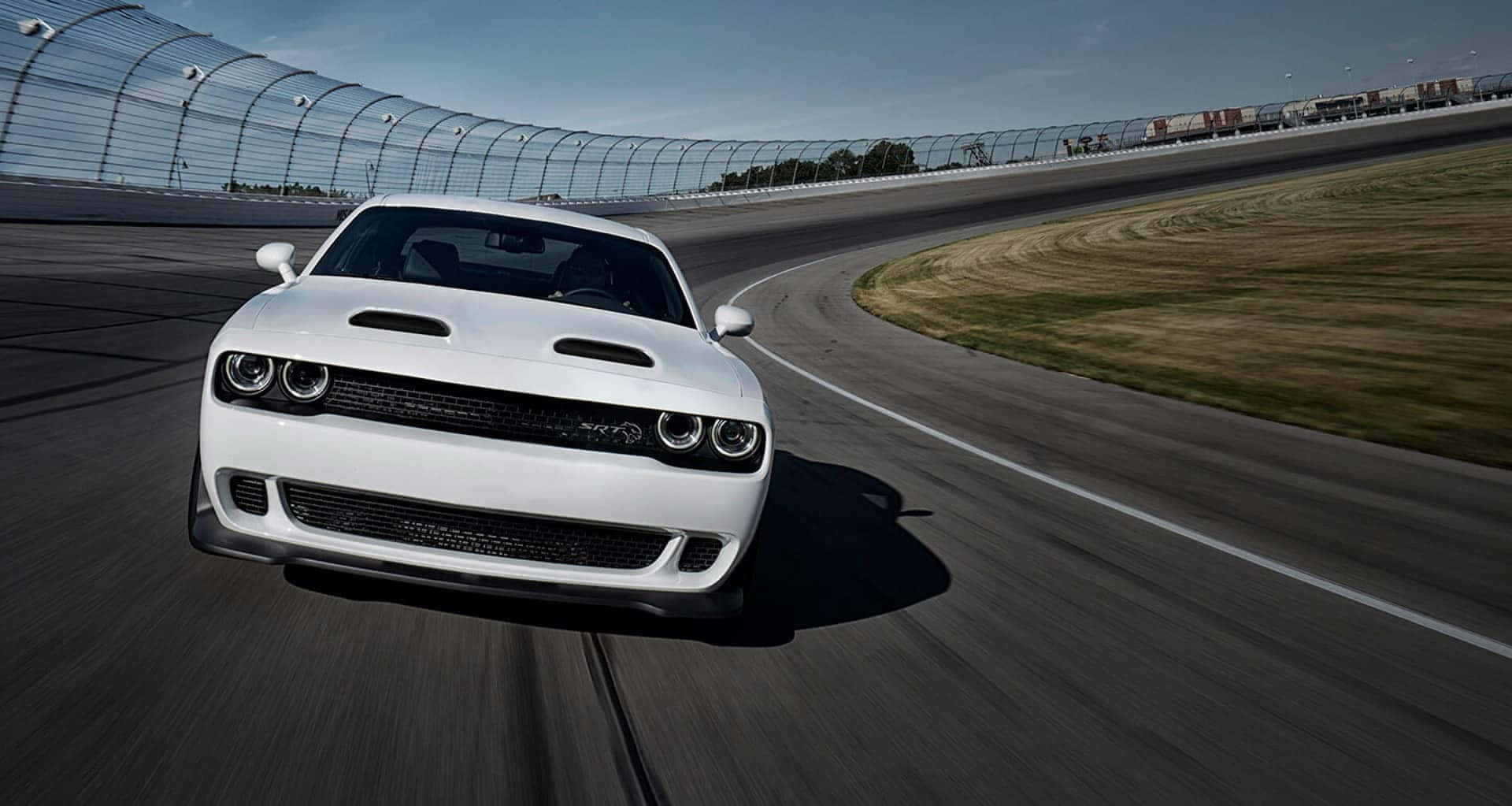 The White Dodge Challenger Is Driving On A Race Track