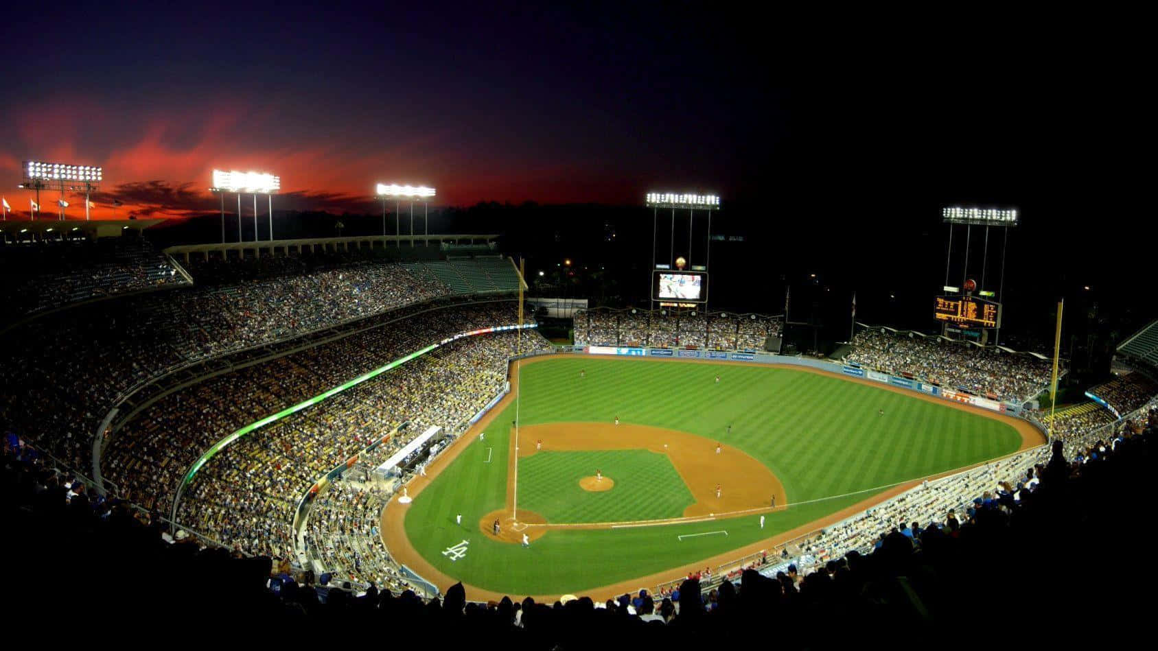 Et baseballstadion om natten med lys tændt. Wallpaper