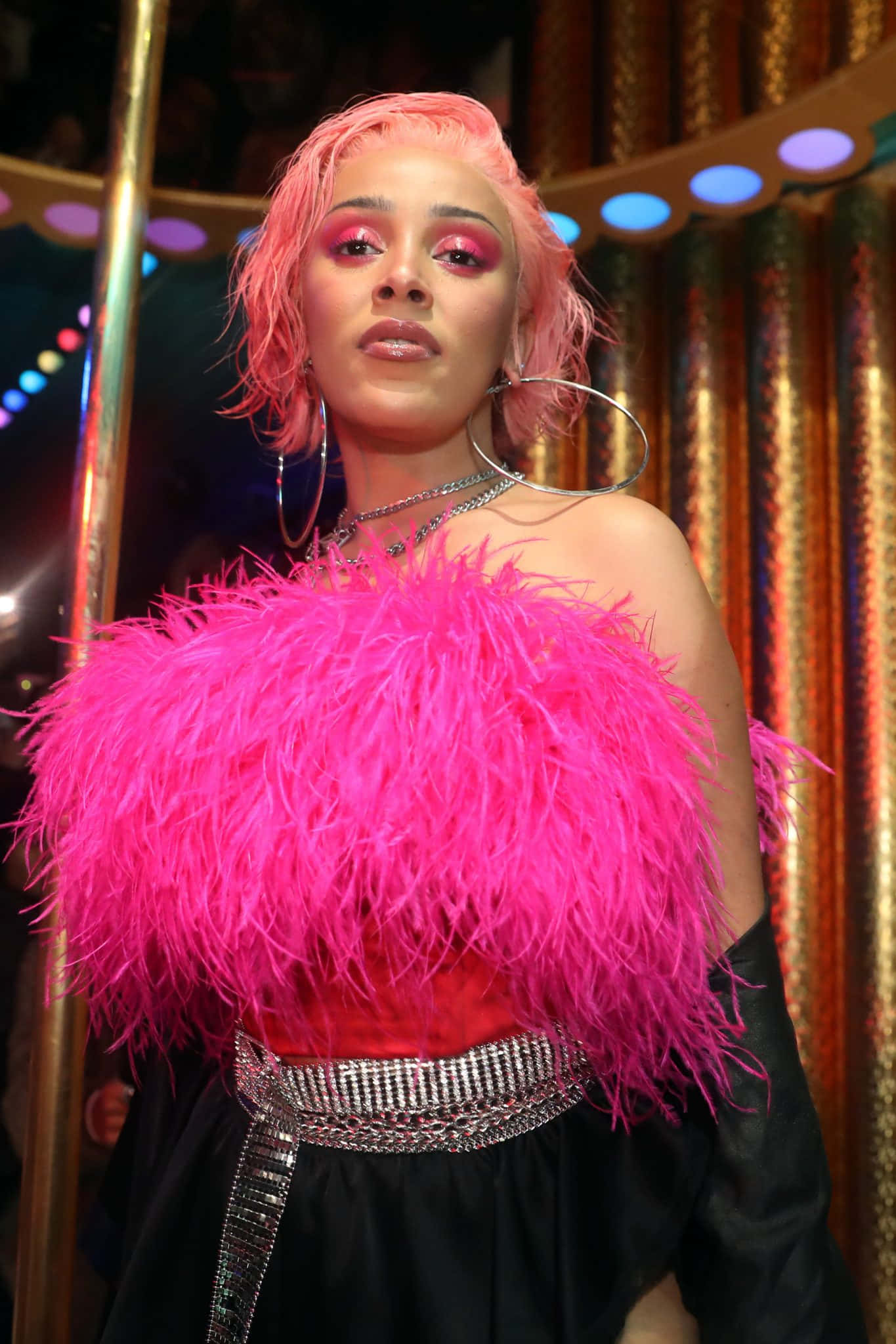 A Woman In A Pink Feathered Dress Is Standing In Front Of A Bar