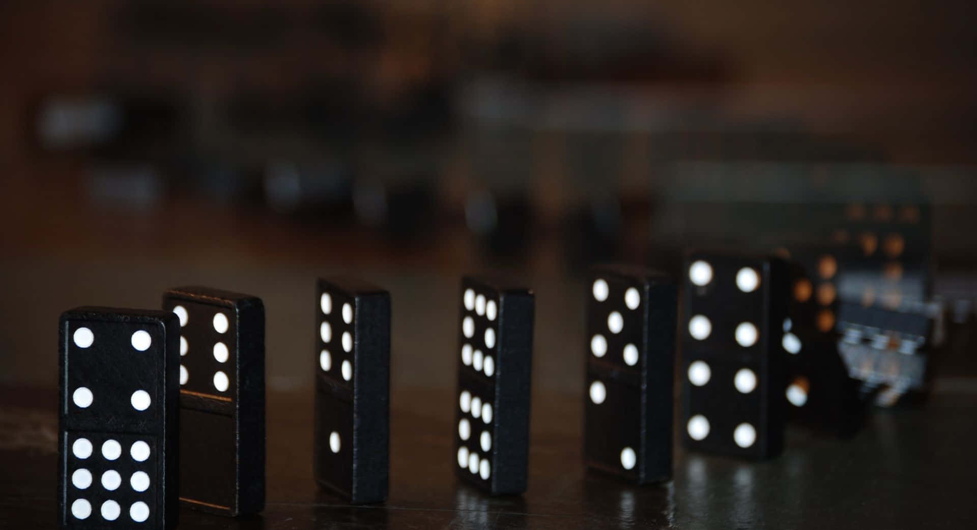 Domino pieces falling in sequence on a black background.