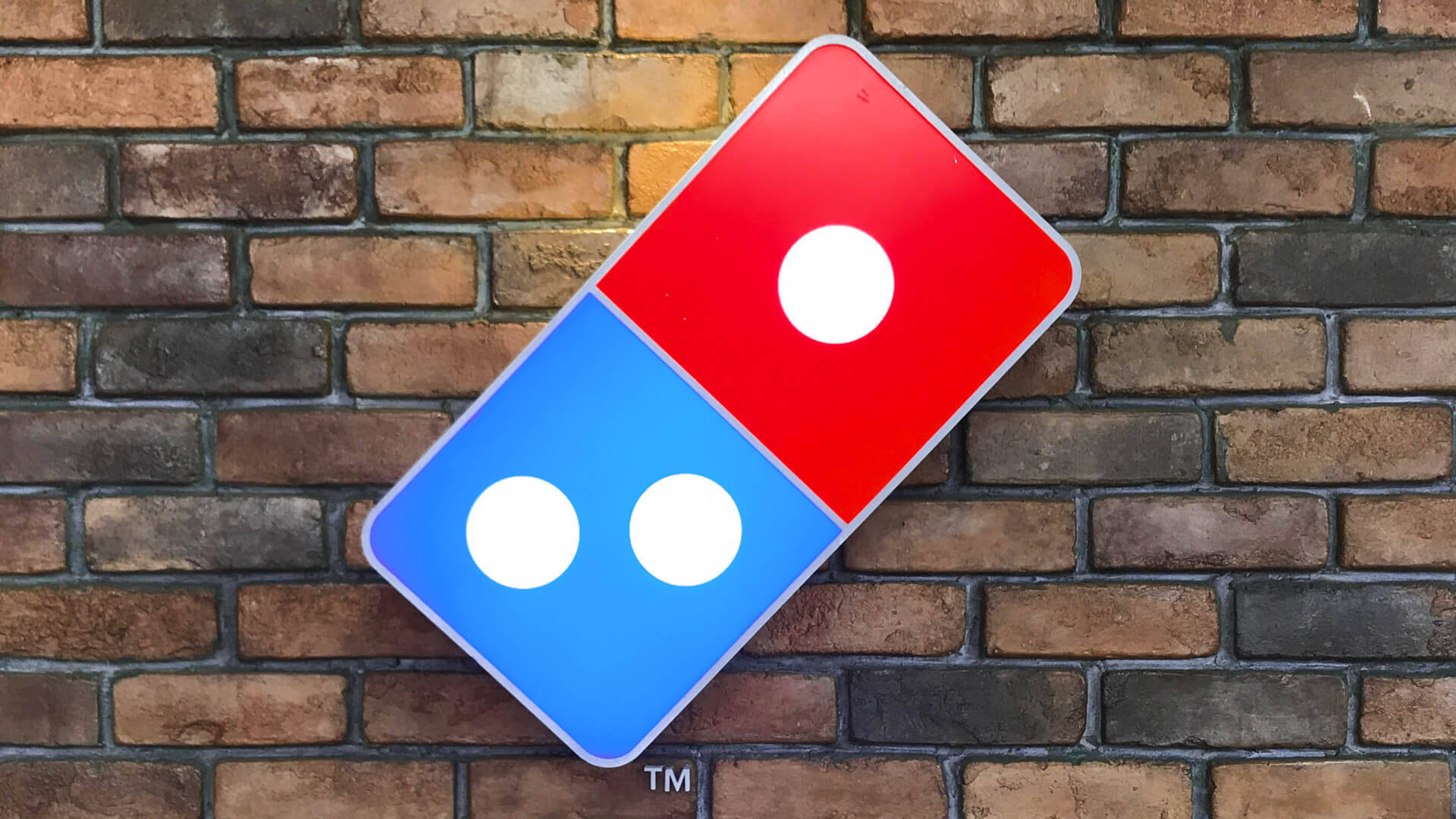 Logotipode Dominos Pizza En Una Pared De Ladrillo. Fondo de pantalla