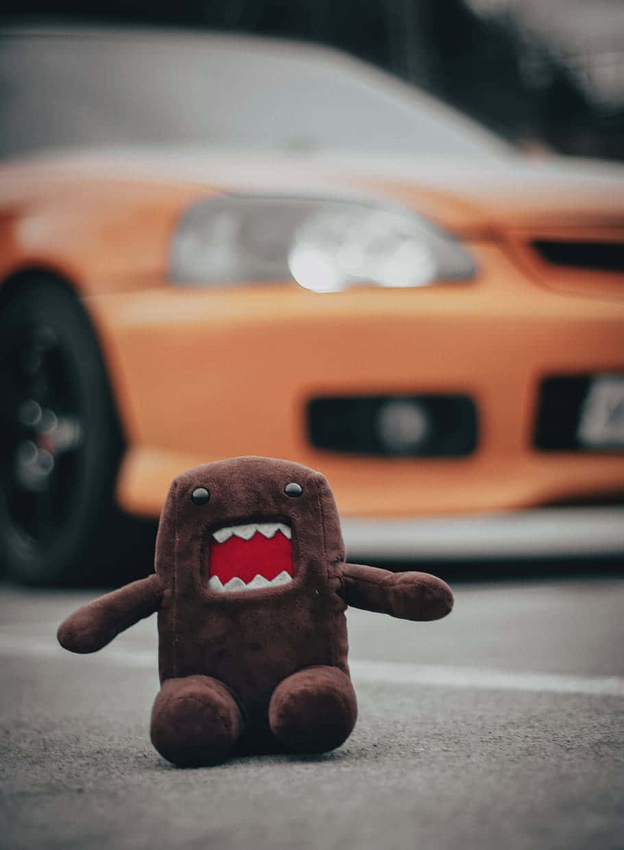 Domo Kun Toy In Front Of Orange Car Wallpaper