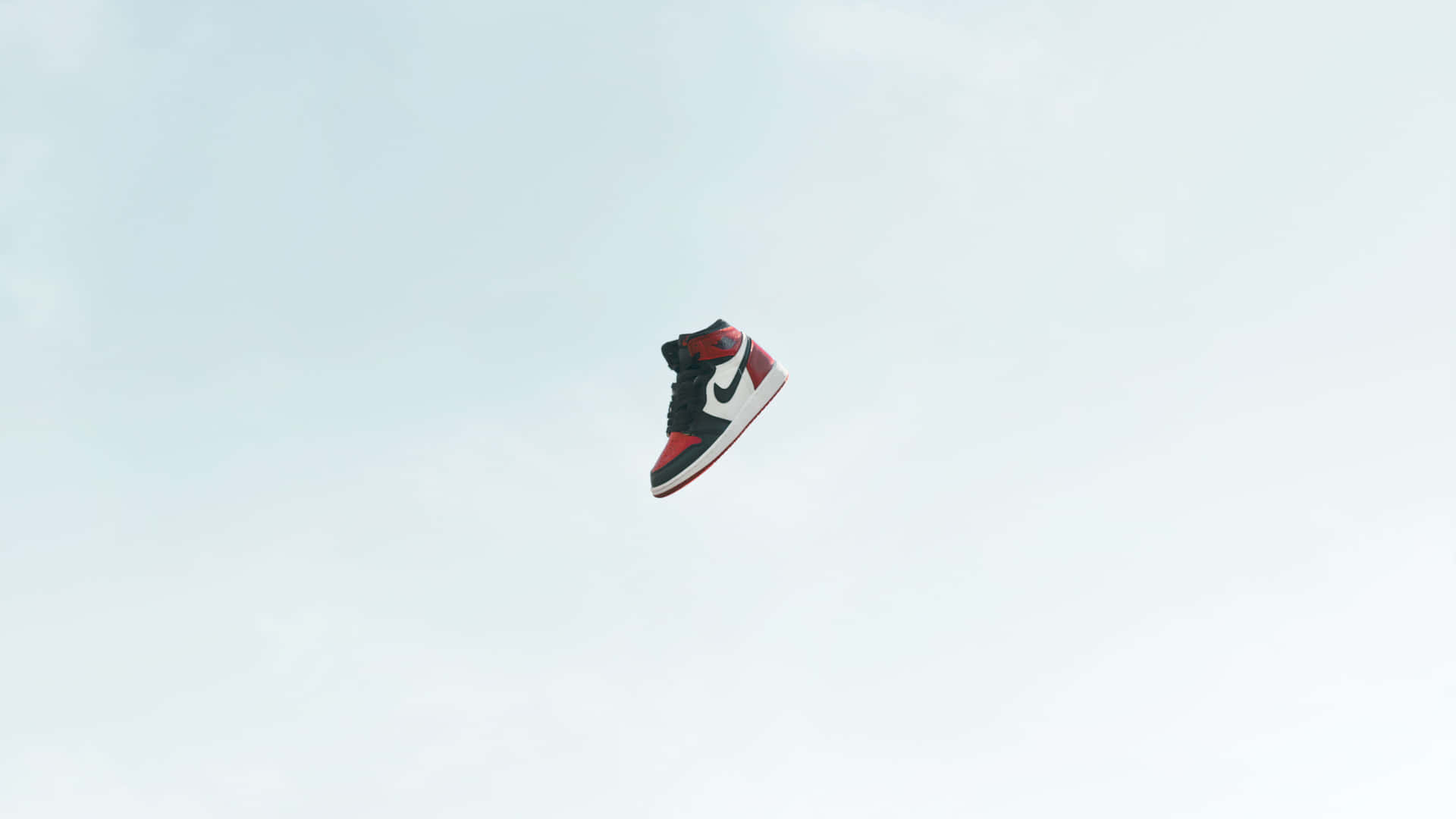 a pair of sneakers flying through the air Wallpaper