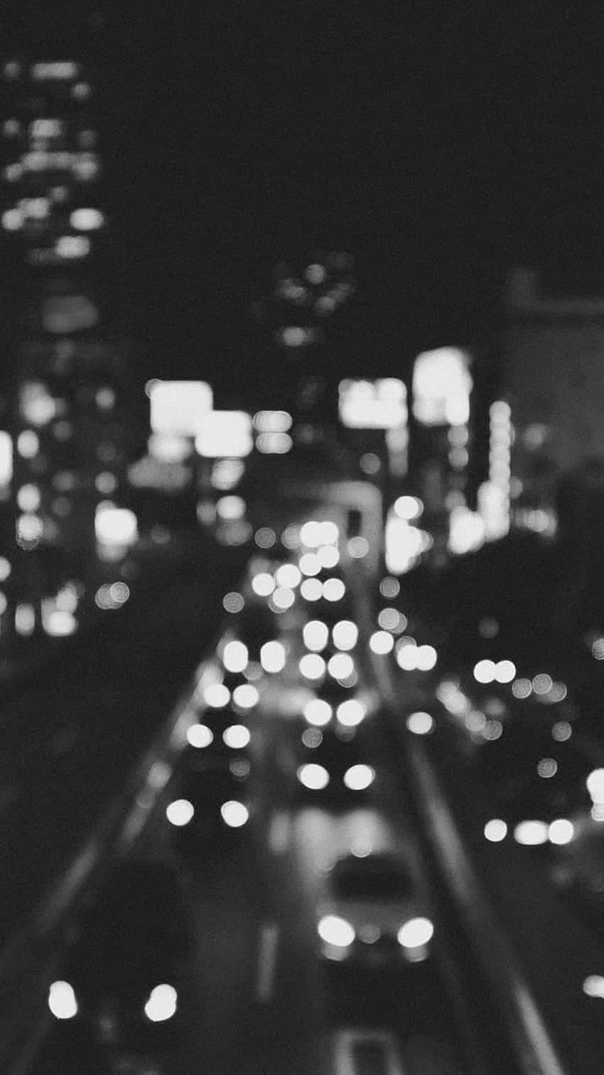 Et sort og hvidt foto af en by om natten Wallpaper