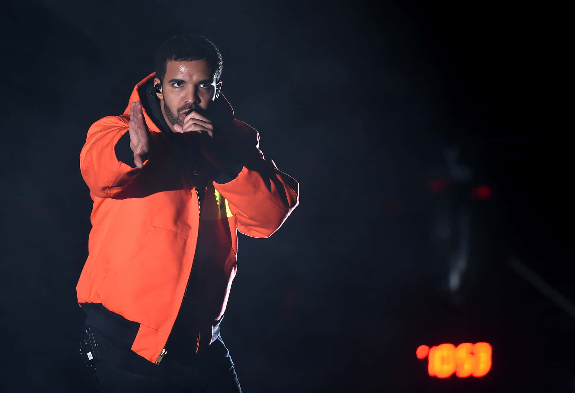 Drake optræder på scenen i en orange jakke Wallpaper