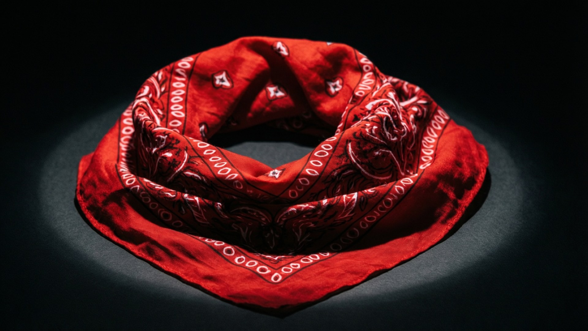A red bandana under dramatic lighting on a black background.