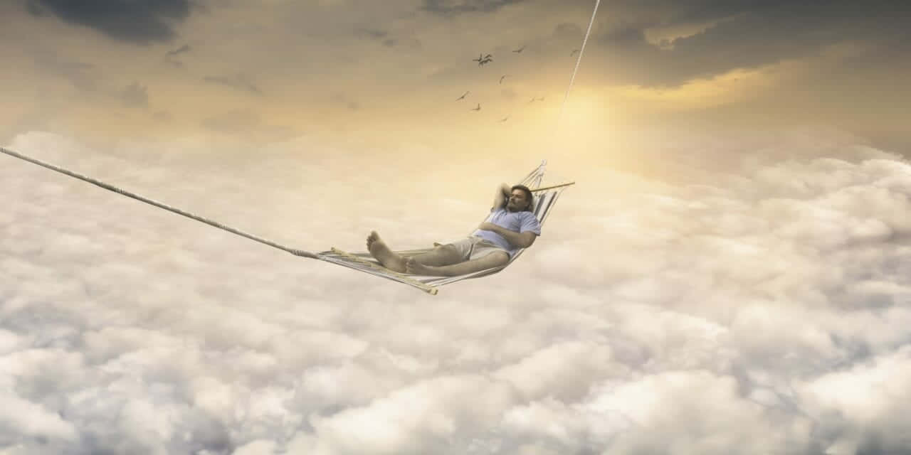 A Man Is Sitting In A Hammock In The Clouds