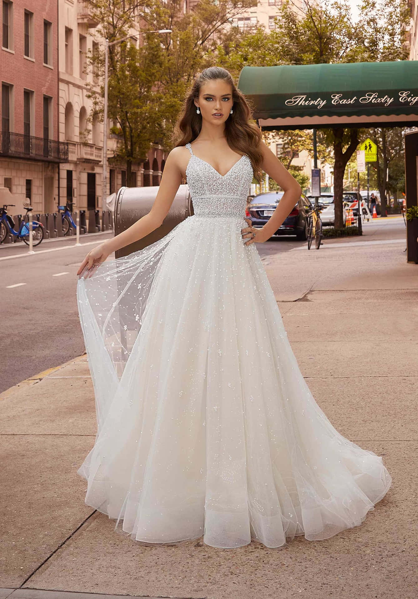 A Woman In A Wedding Dress Is Standing On The Sidewalk