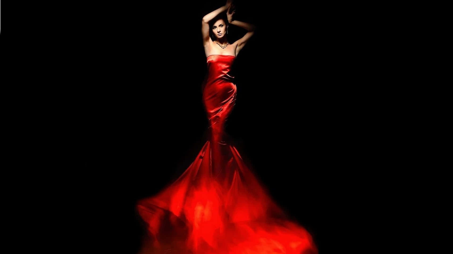 A Woman In A Red Dress Is Posing In The Dark