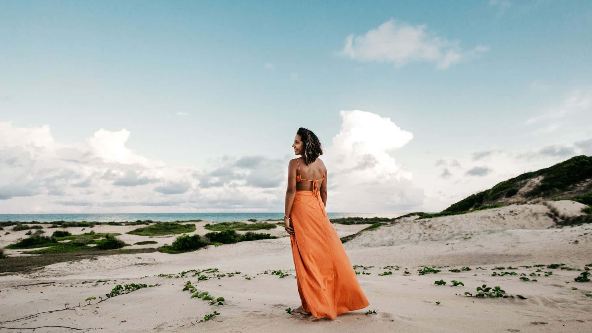 Enkvinna I En Orange Klänning Står På Stranden