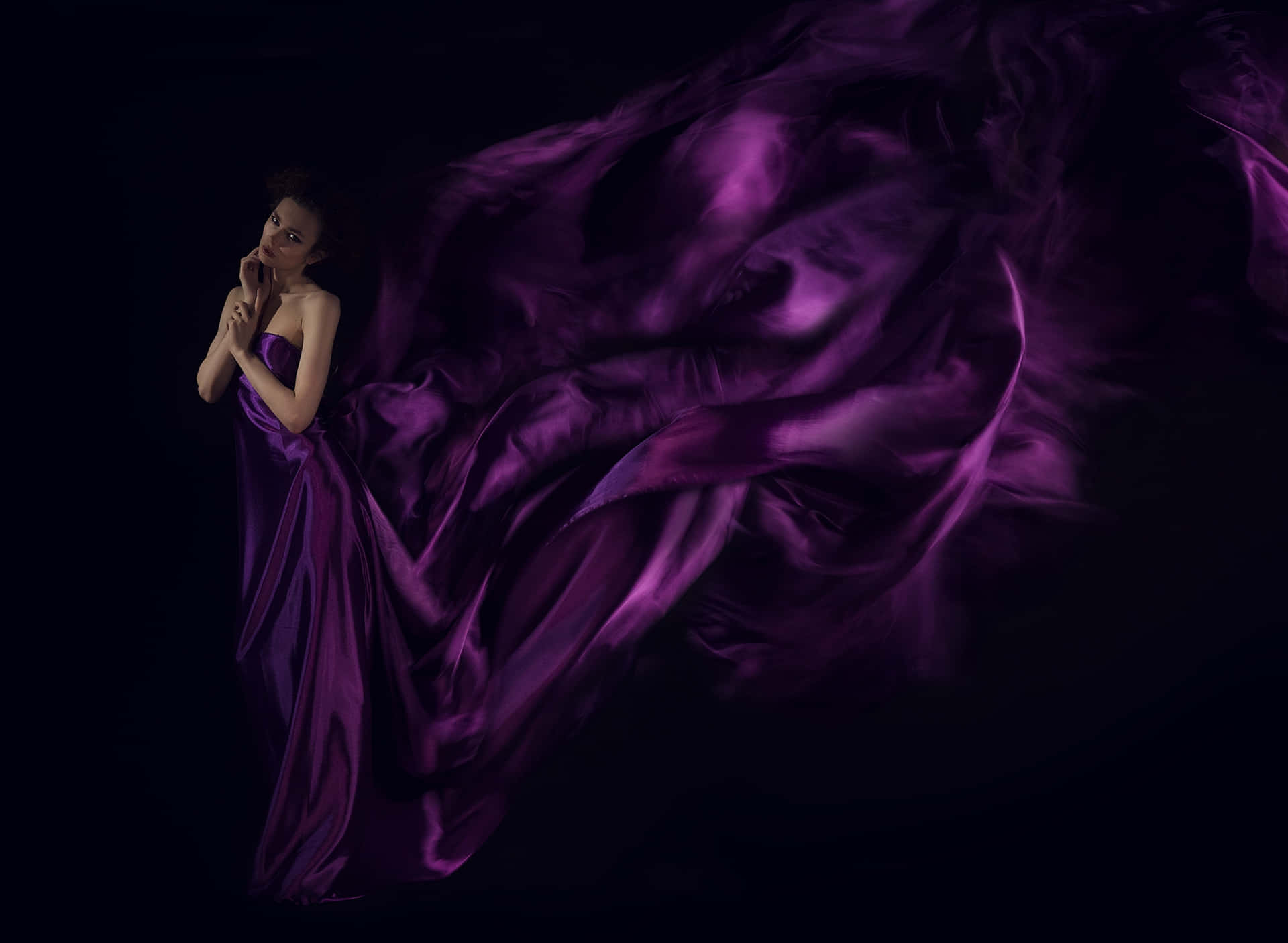 Einefrau In Einem Violetten Kleid Steht Vor Einem Schwarzen Hintergrund.