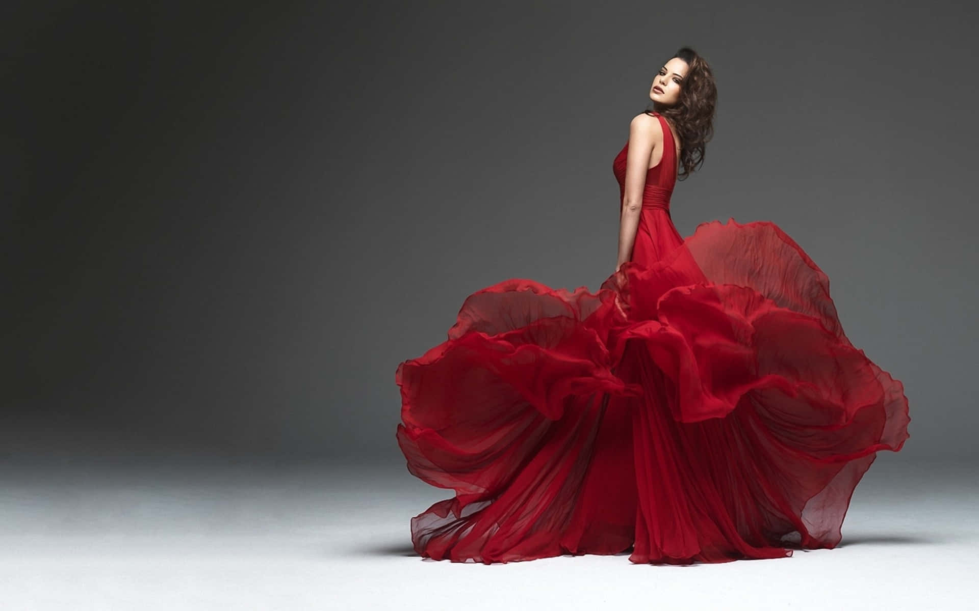 A Woman In A Red Dress Is Posing