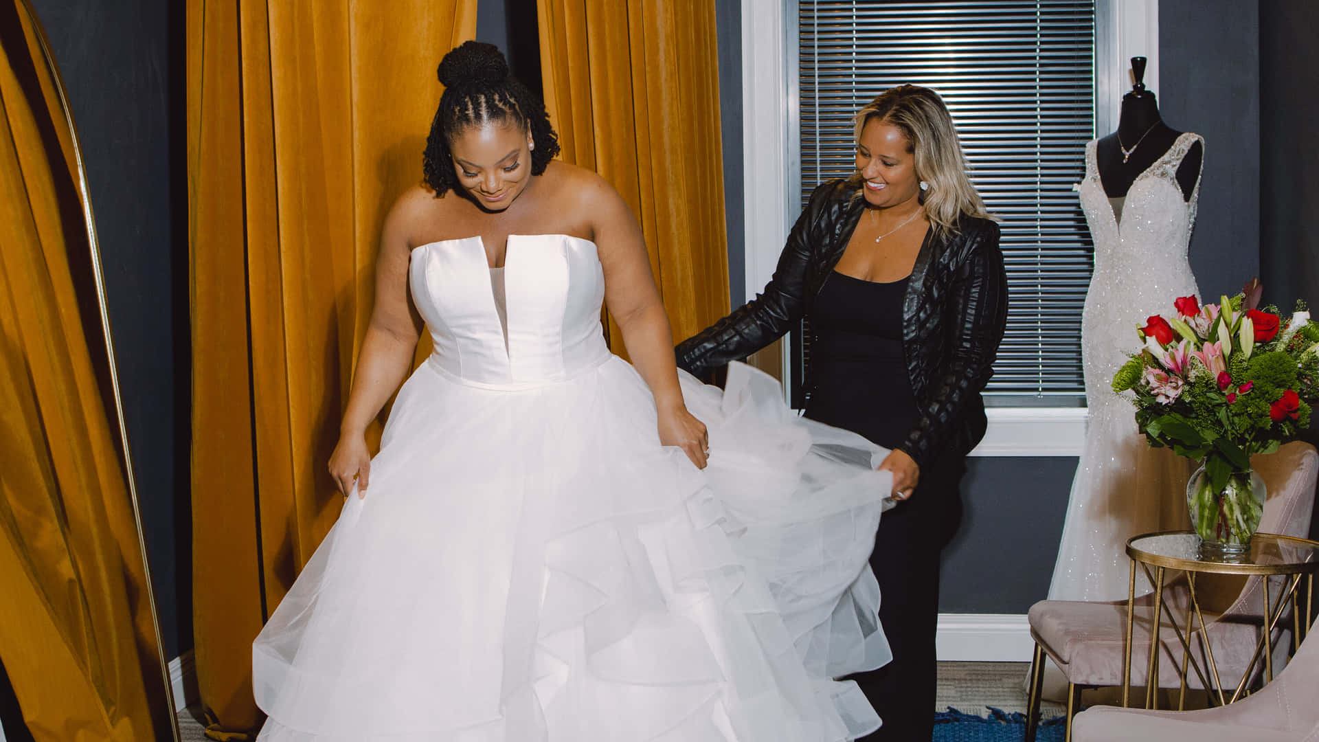 A Woman Is Helping Another Woman Put On A Wedding Dress