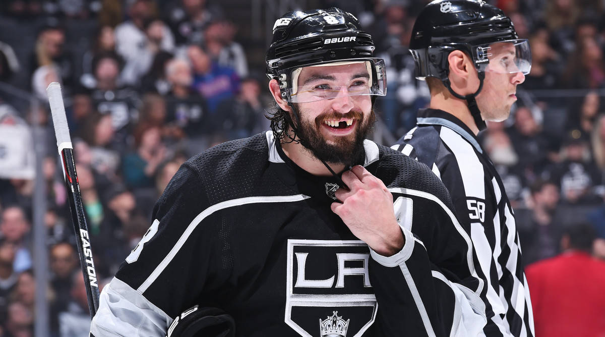 Drew Doughty Smiling With Missing Teeth While Holding Helmet Strap Wallpaper