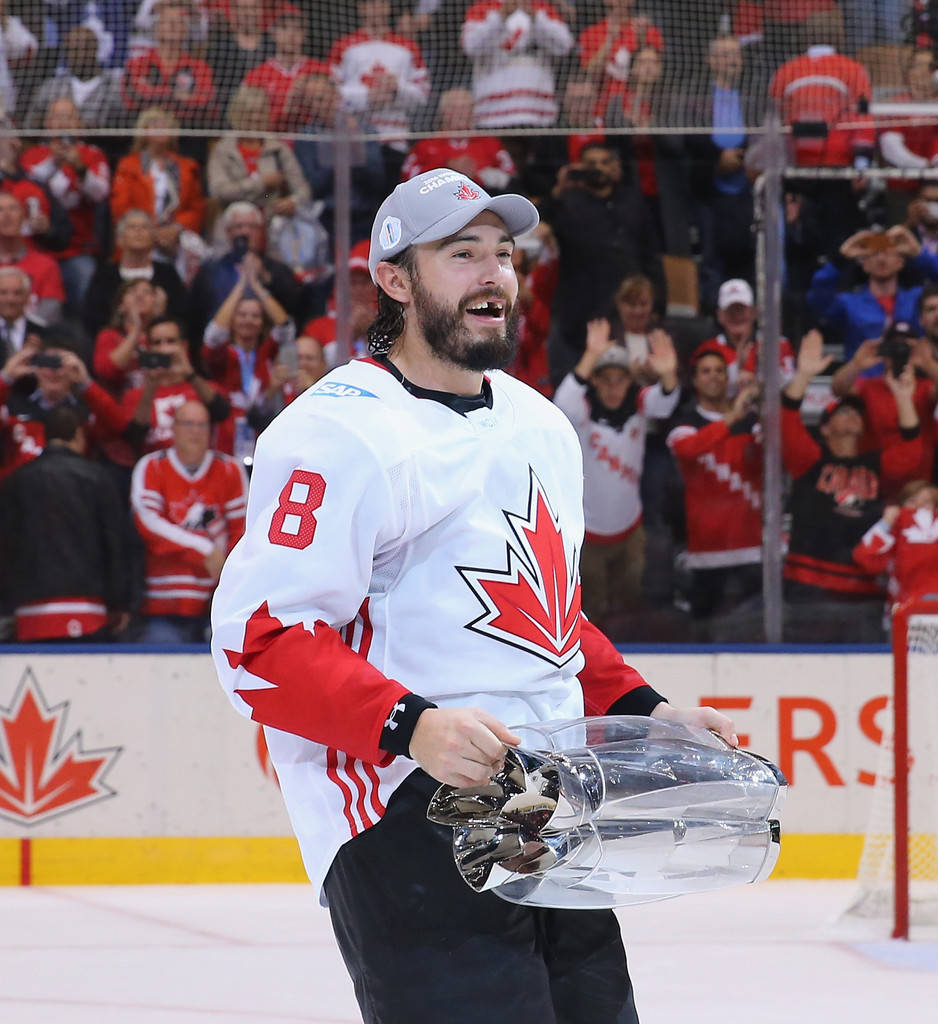 Drew Doughty joyfully holding the World Cup of Hockey trophy, showcasing his characteristic missing-tooth grin Wallpaper