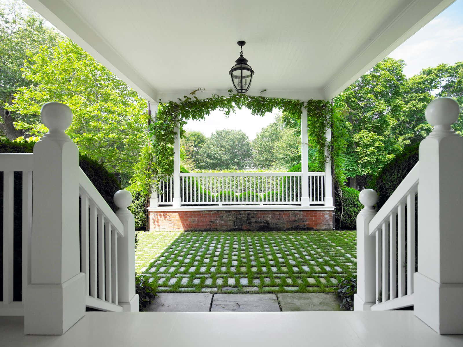 A White Porch With A White Railing And Green Grass