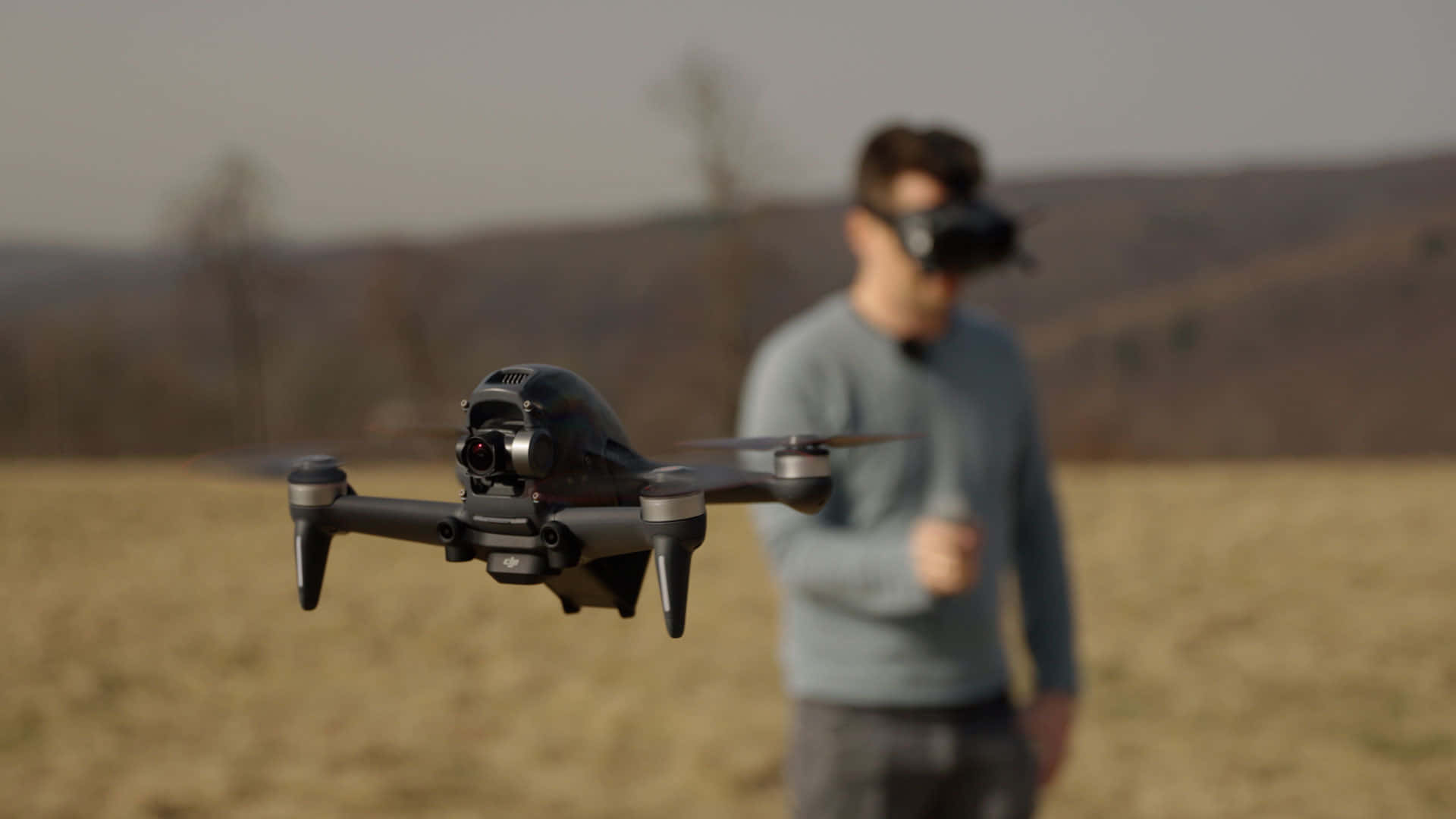 A Man Is Flying A Small Drone In A Field