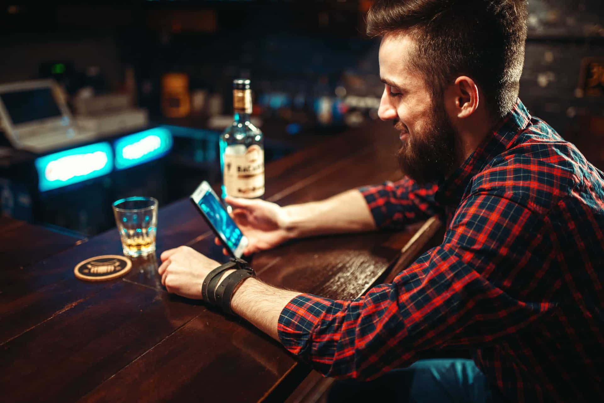A Man Is Using His Phone At A Bar