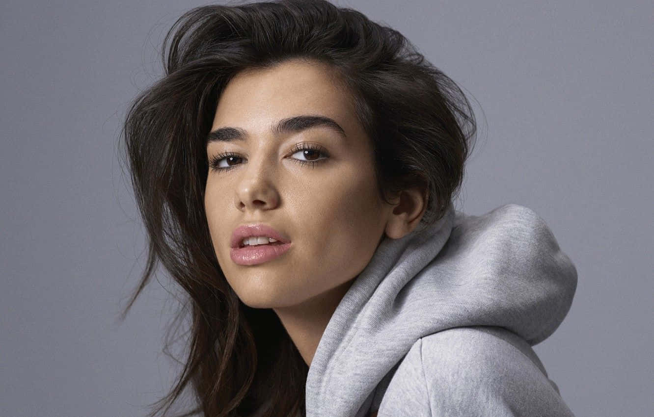 Dua Lipa posing during a photoshoot in a stylish outfit