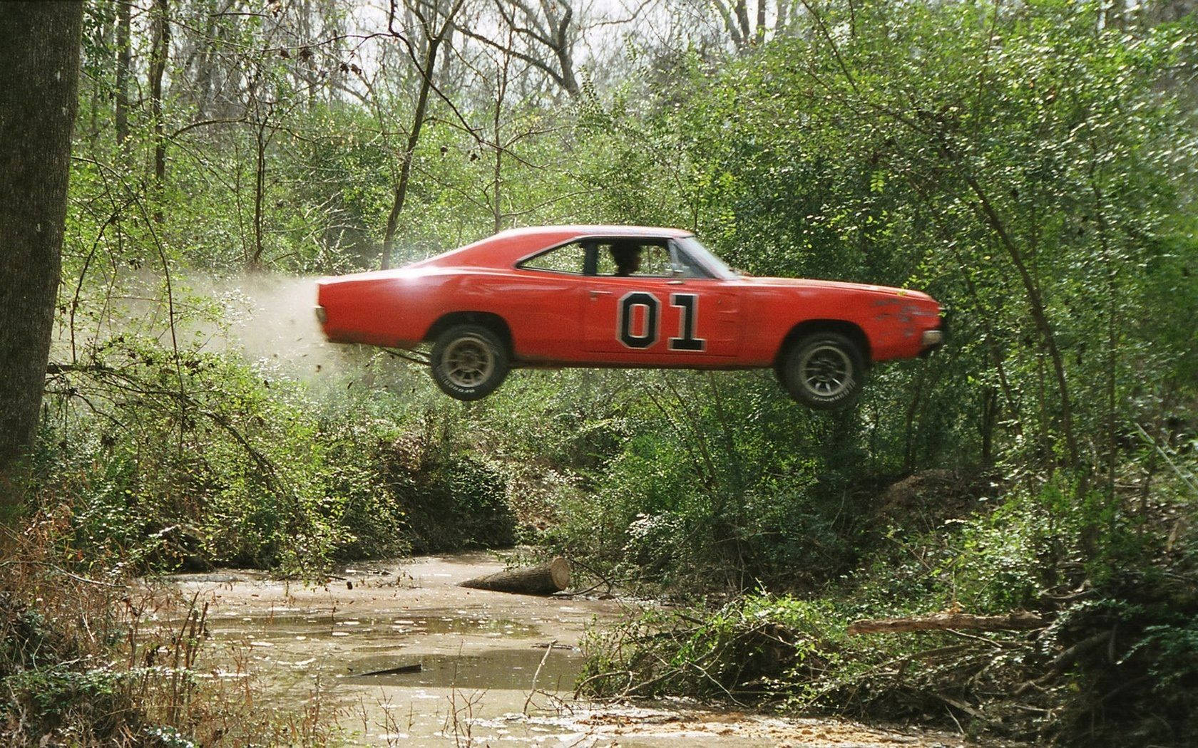A Red Car Is Flying Over A Stream Wallpaper