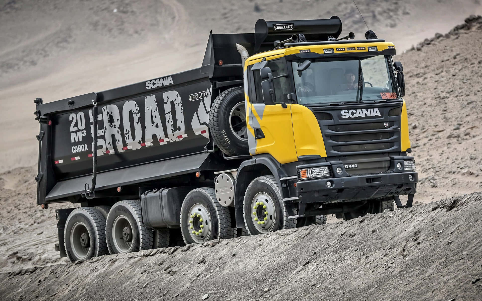 A Large Dump Truck Driving Down A Dirt Road